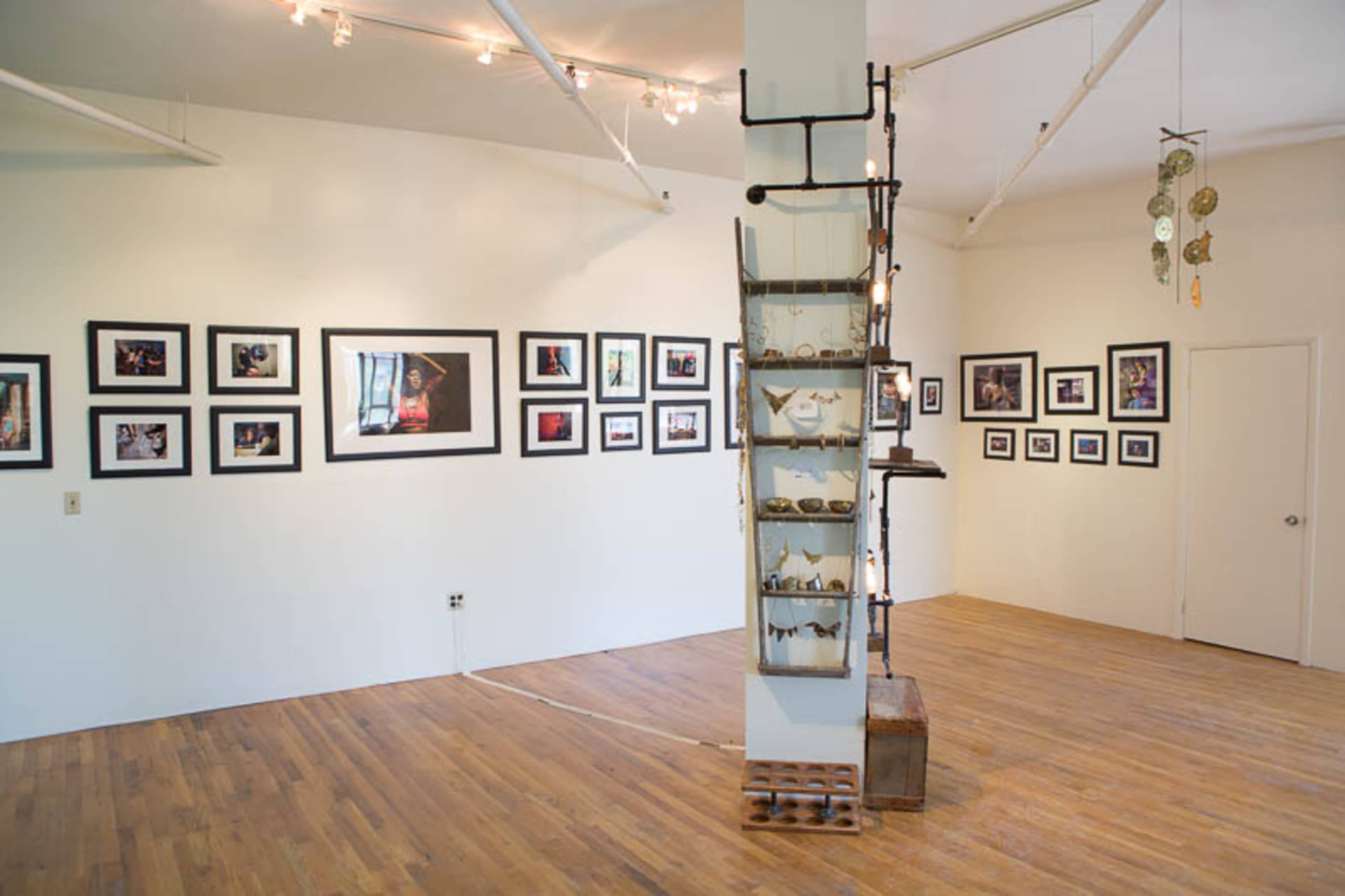 An art gallery interior with framed photographs displayed on the walls and a vertical exhibit structure in the center.