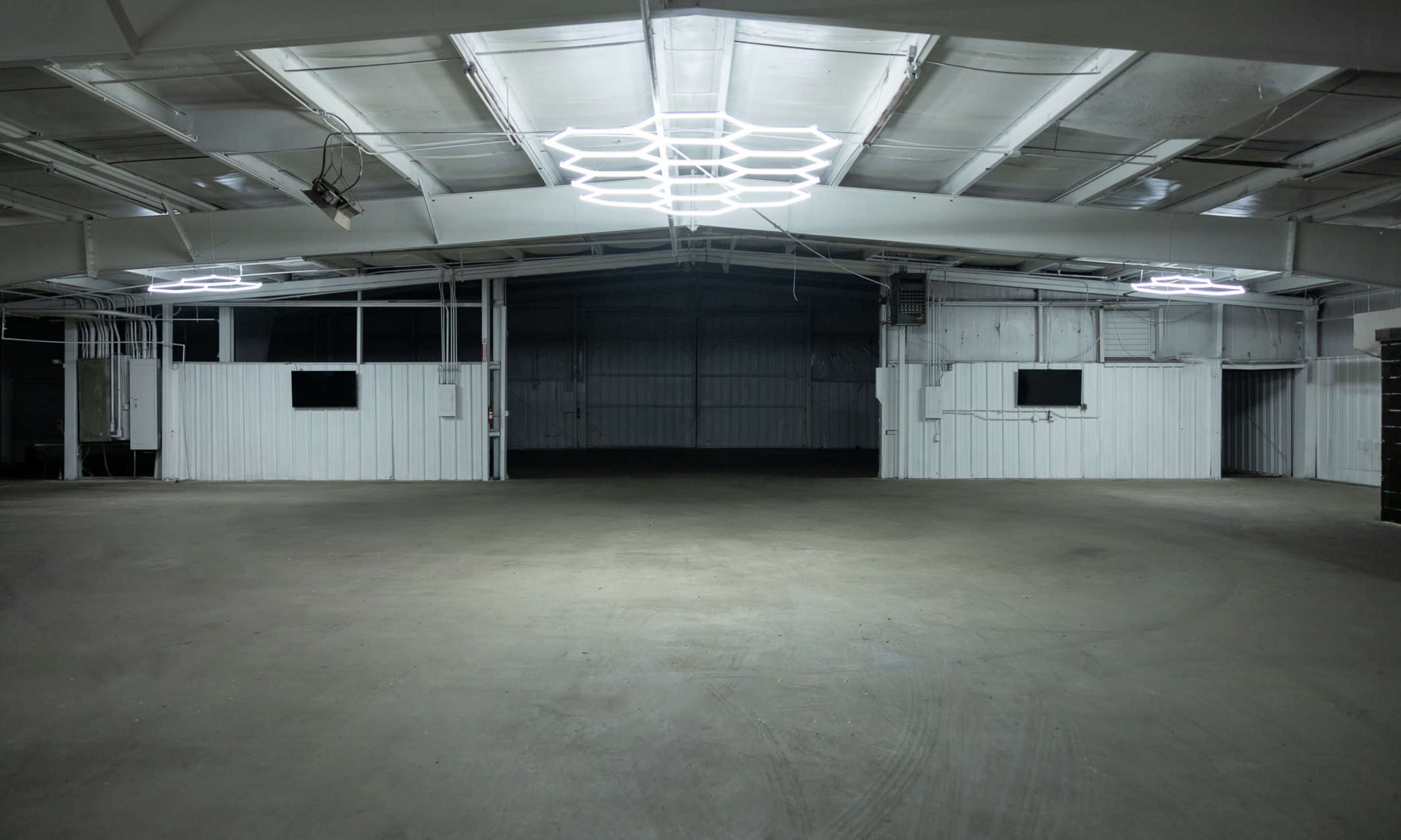 An empty industrial space features a high ceiling with modern light fixtures and white walls.