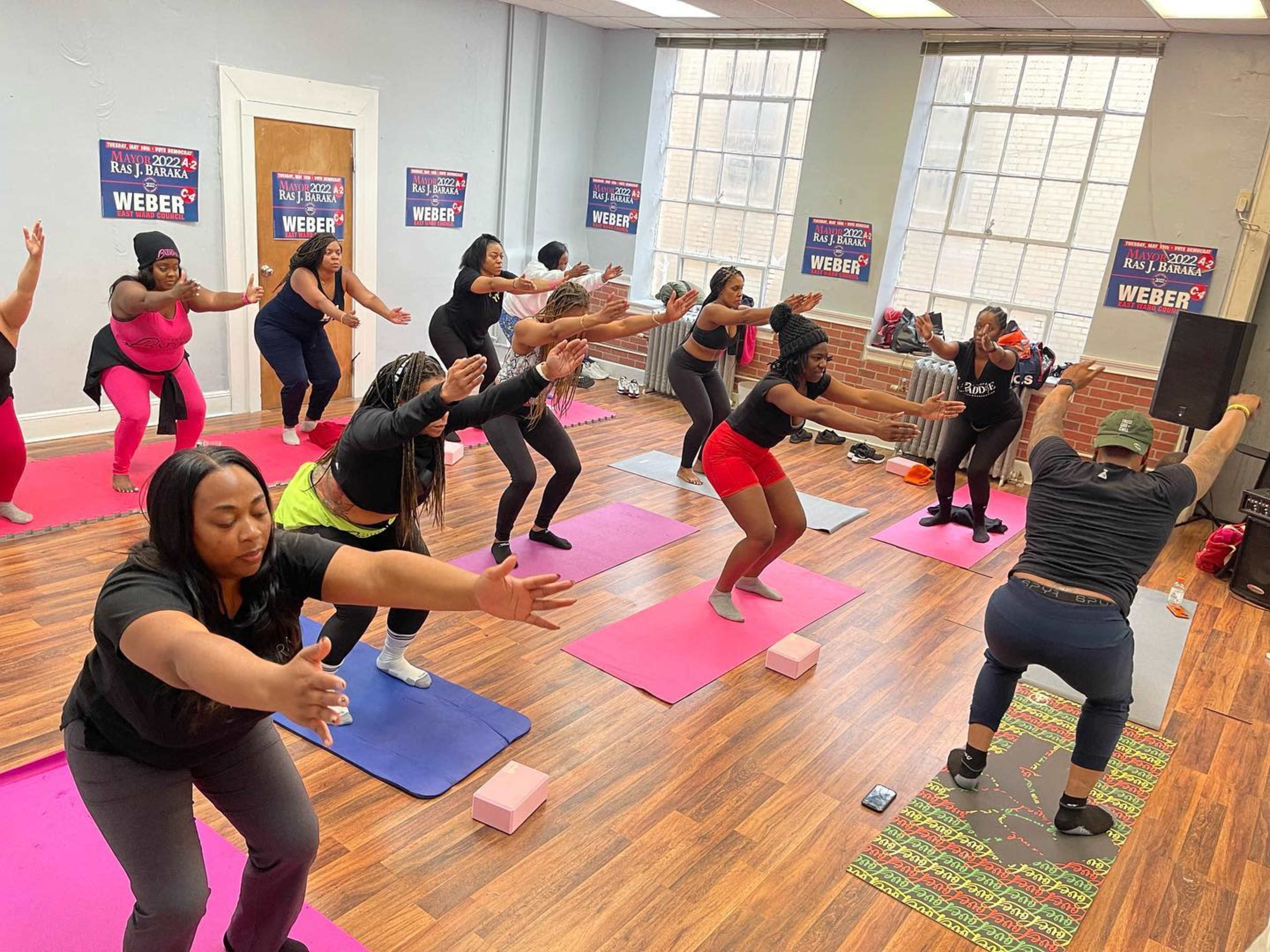 A group of women participates in a fitness class using yoga mats in a brightly lit room.