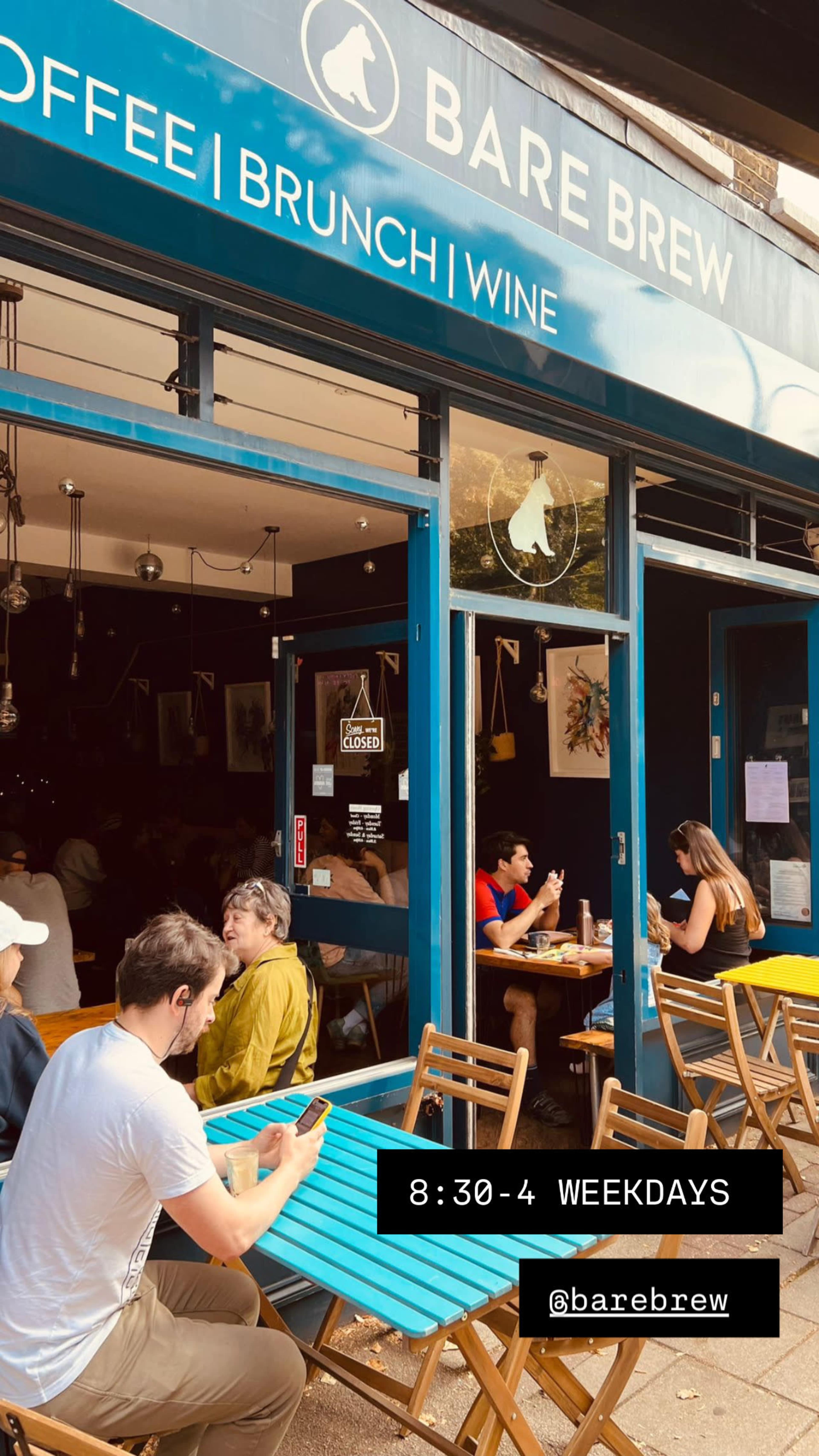 A café named Bare Brew features outdoor seating with customers engaged in conversation and using their phones.