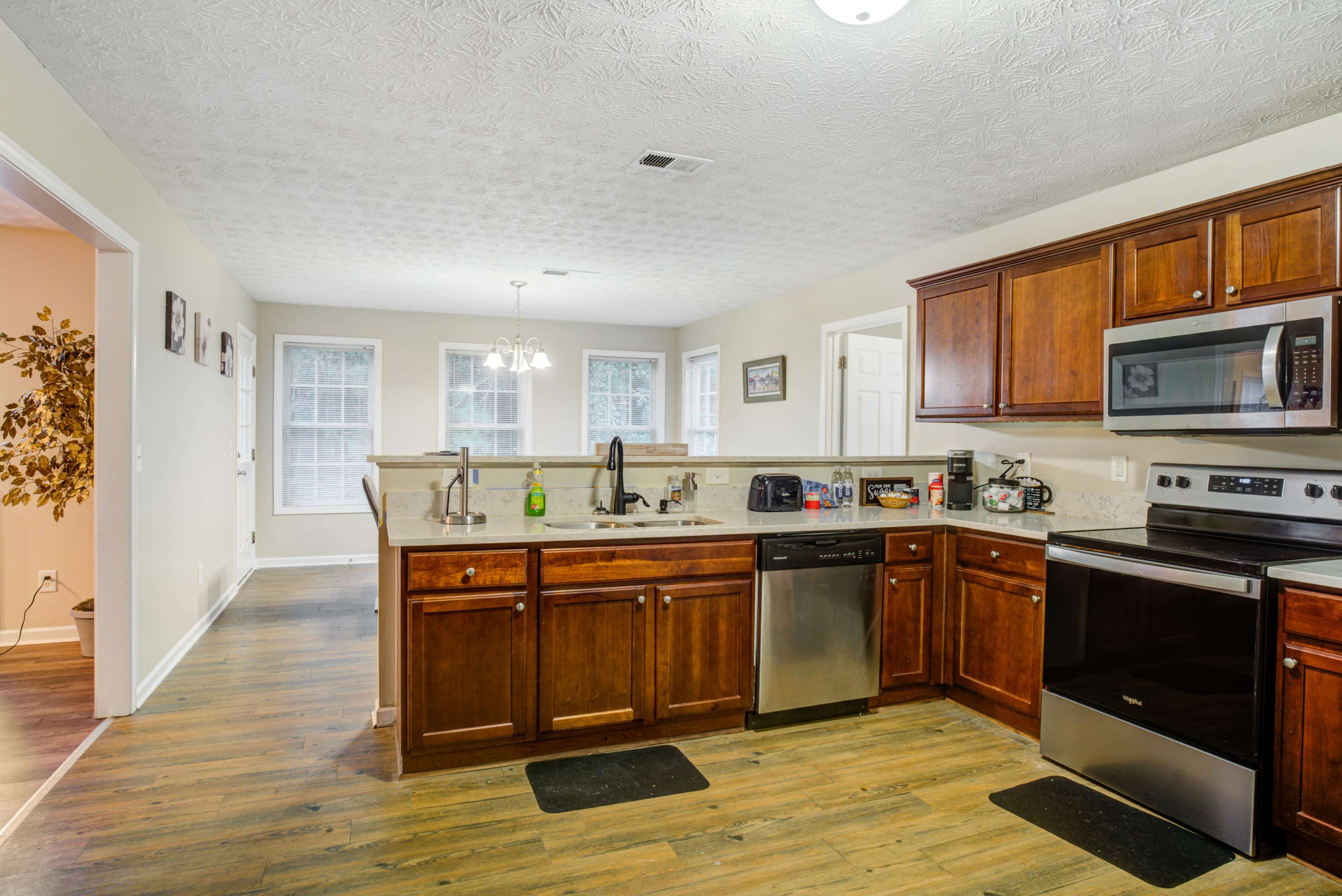 A spacious kitchen with wooden cabinets, stainless steel appliances, and a light-colored wall.