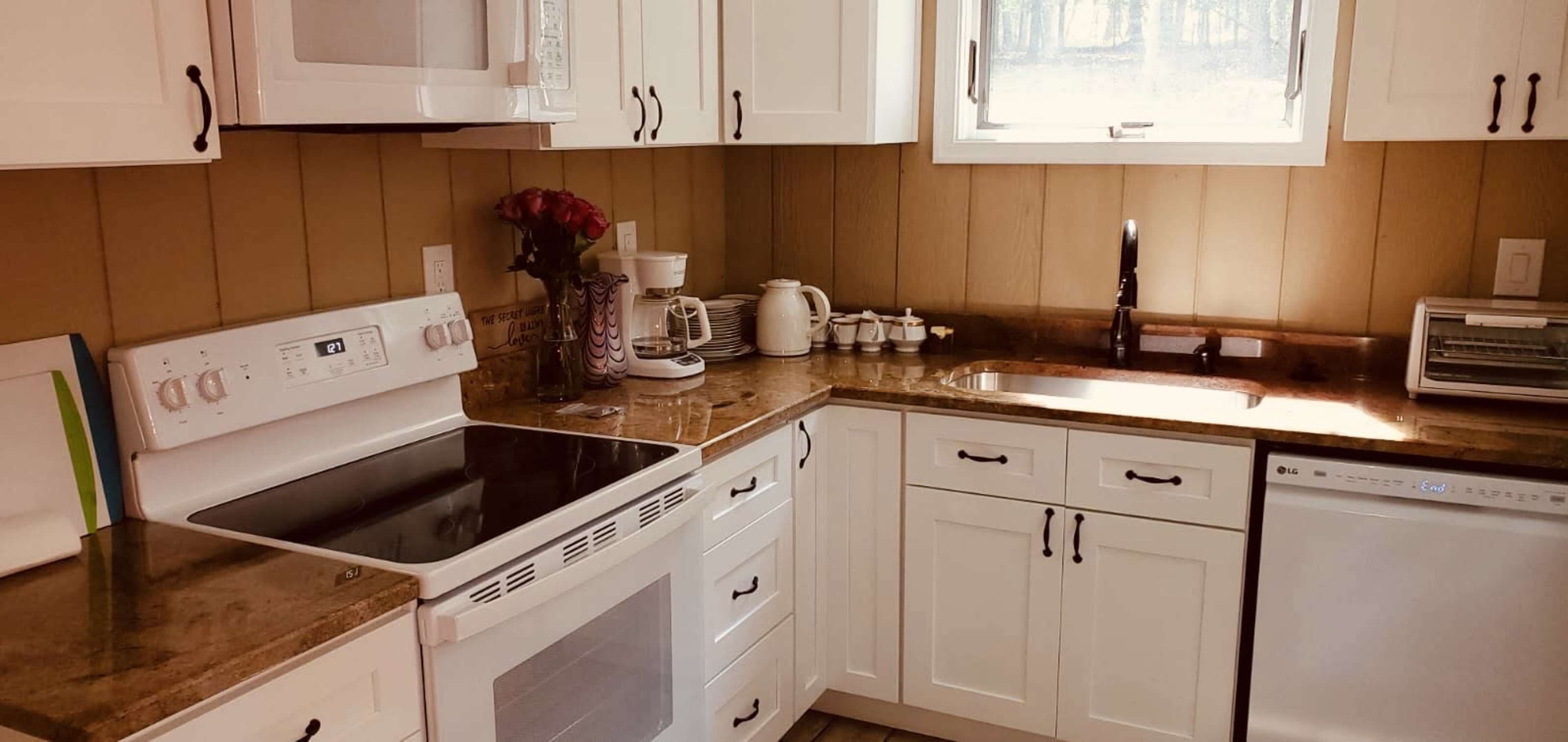 A modern kitchen features white cabinetry, a dark countertop, and stainless steel appliances, including a dishwasher and a microwave.