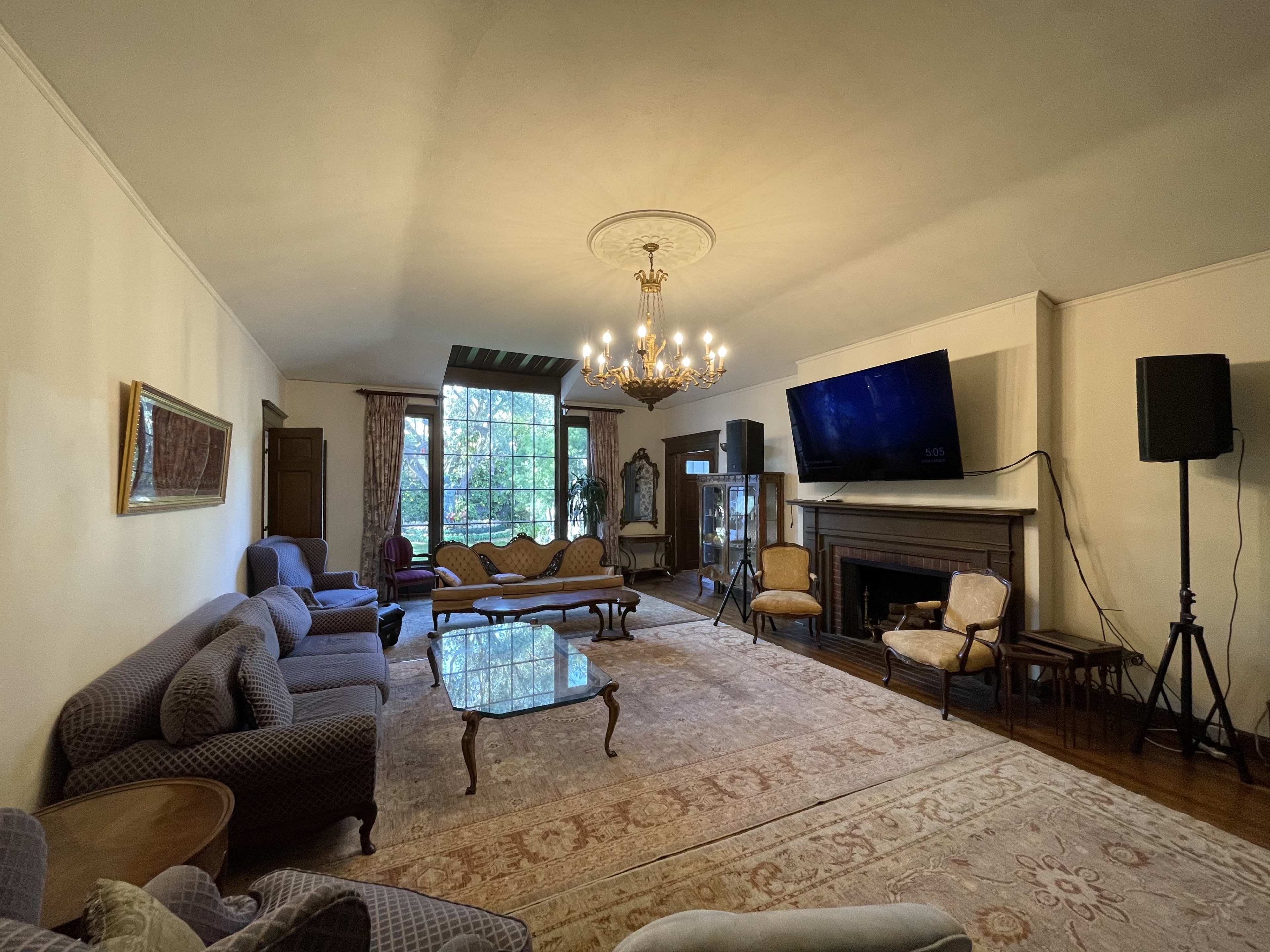 A spacious living room with a chandelier, two couches, a coffee table, and large windows that provide a view of the outdoors.