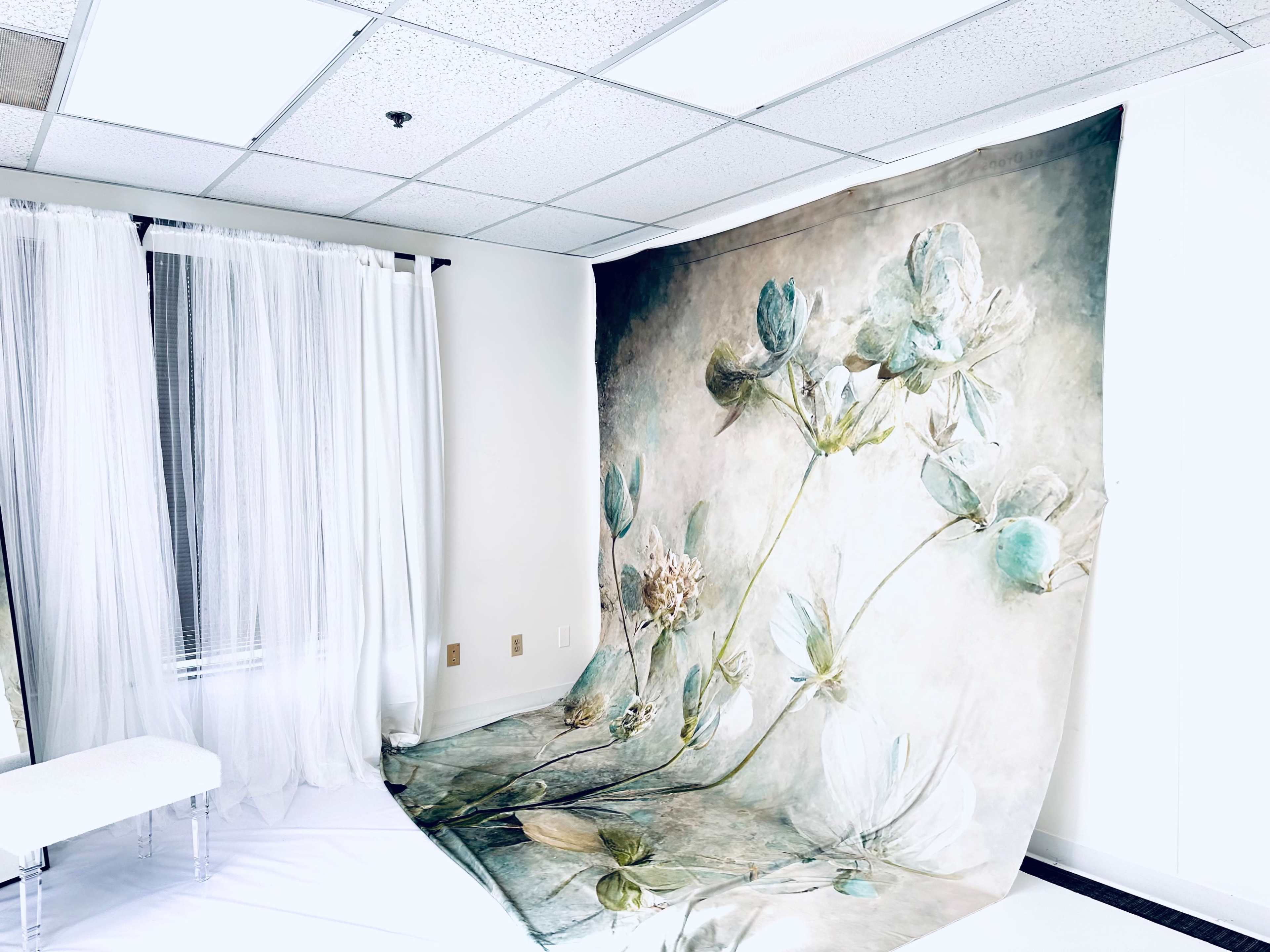 A large floral backdrop is displayed in a bright room with sheer curtains and a white floor.