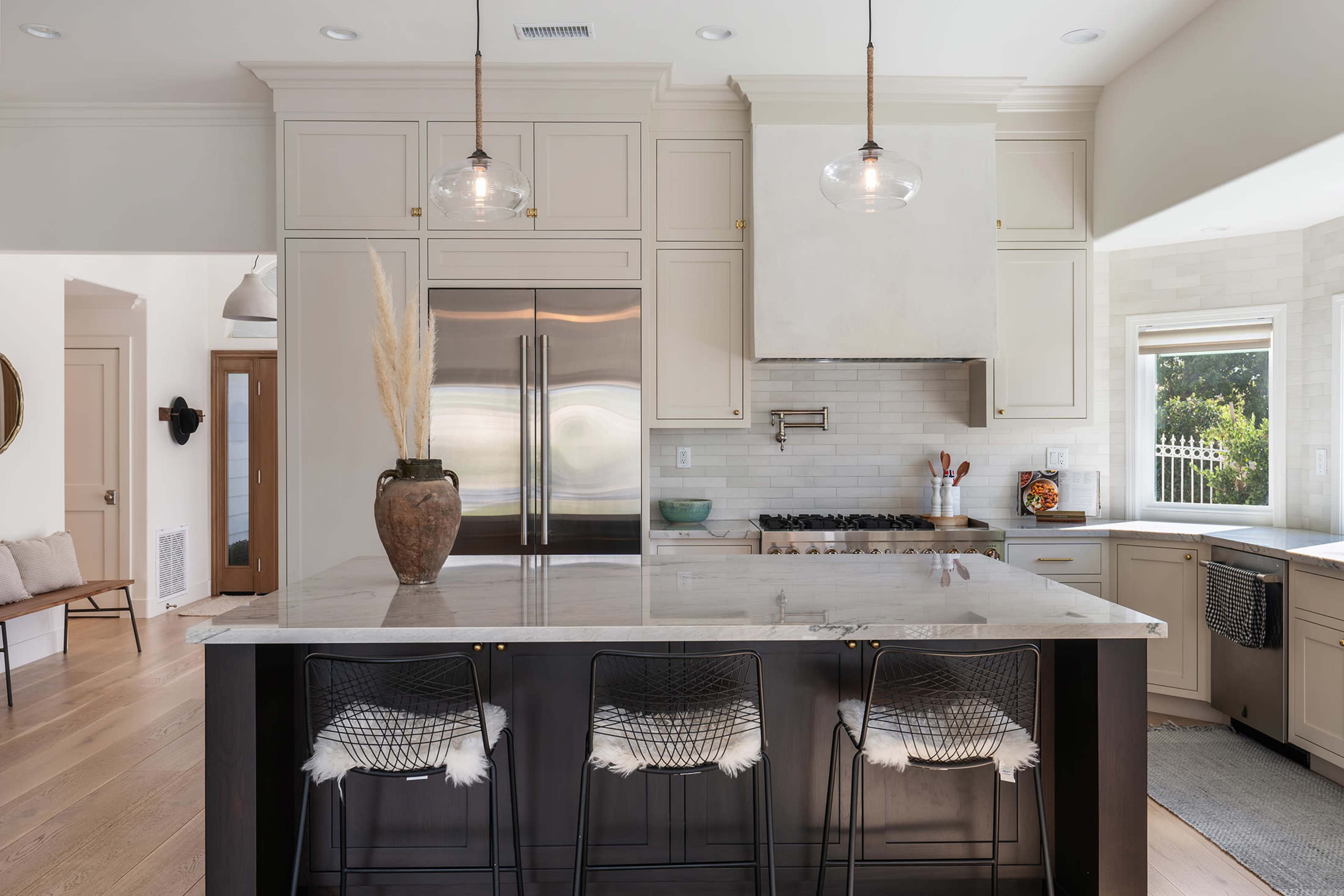A modern kitchen features a large island with seating, sleek cabinetry, and stainless steel appliances.