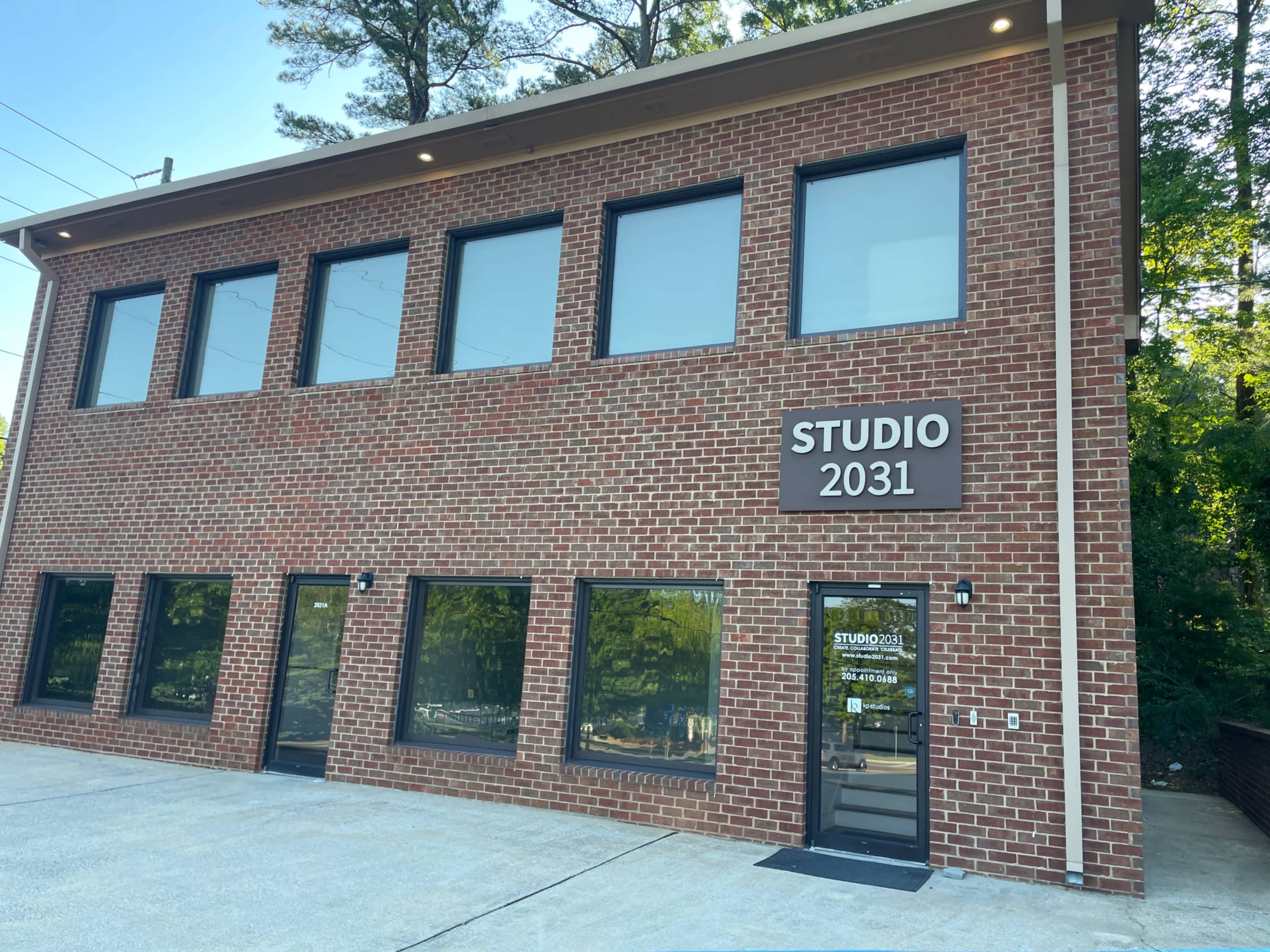 The image shows a two-story brick building with large windows and a sign reading "STUDIO 2031" above the entrance.