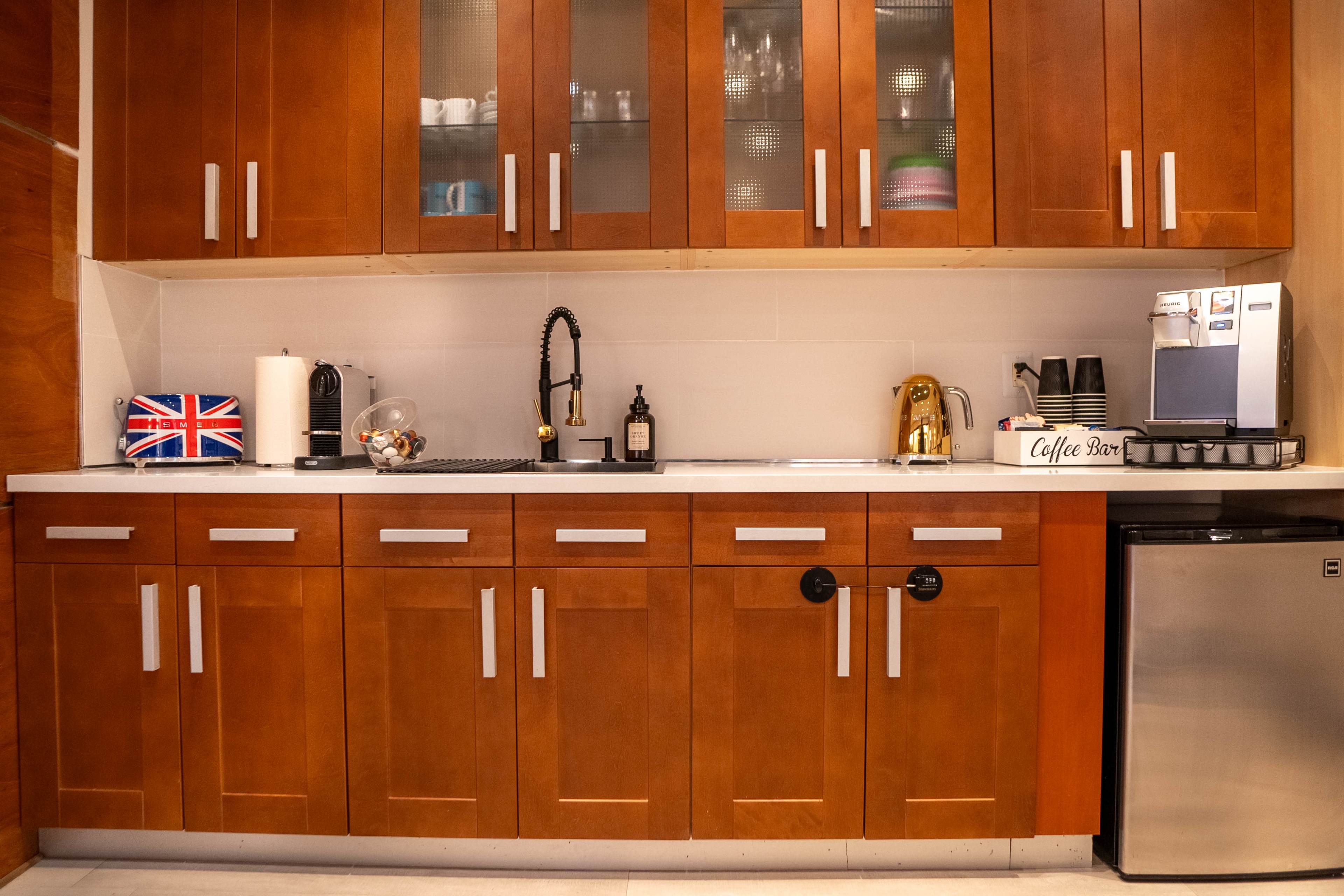 A kitchen with wooden cabinets, a sink with a black faucet, a coffee machine, and an assortment of kitchenware displayed on the countertop.