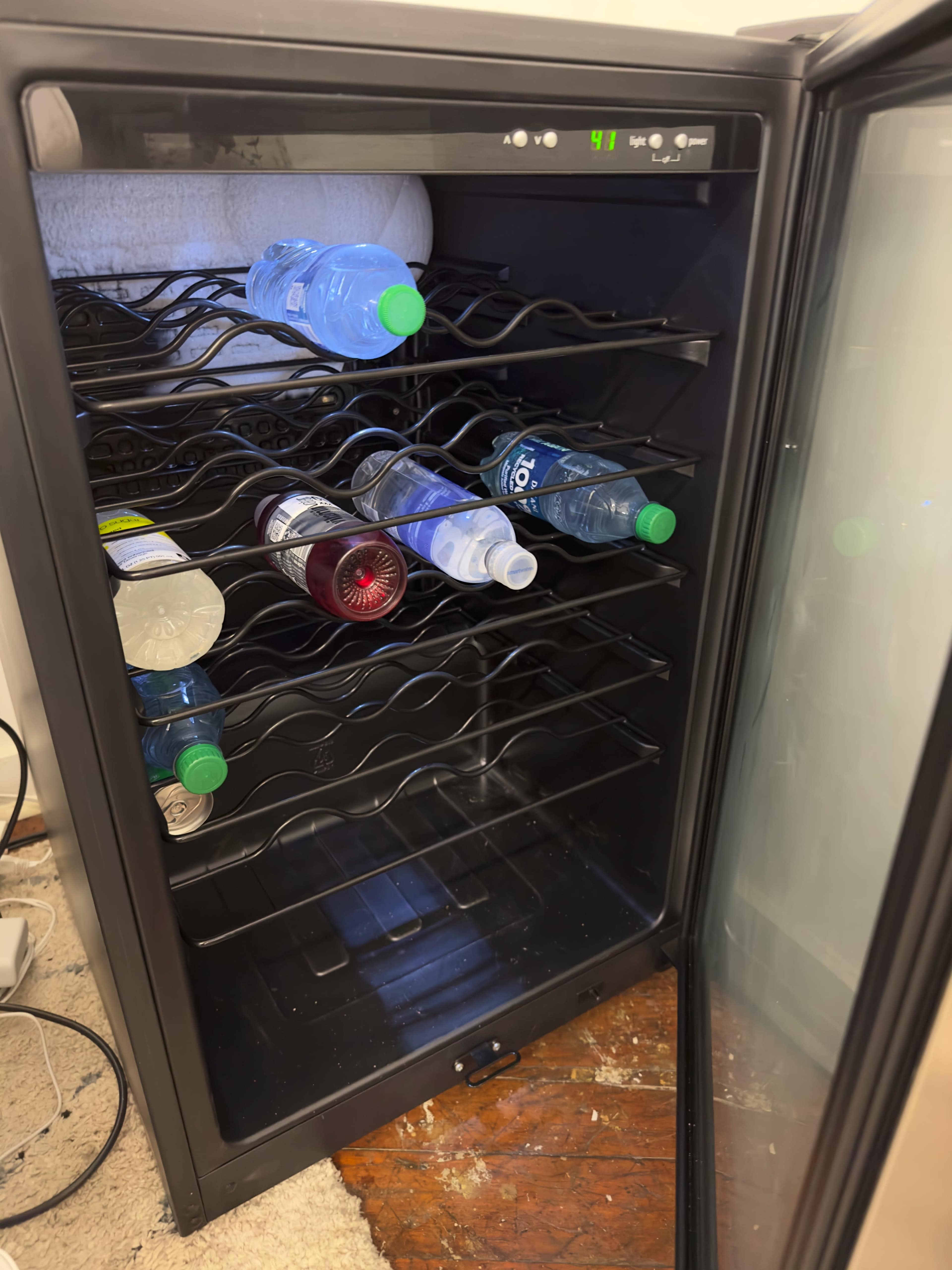 An open refrigerator with several bottles of water and soft drinks arranged on its shelves.