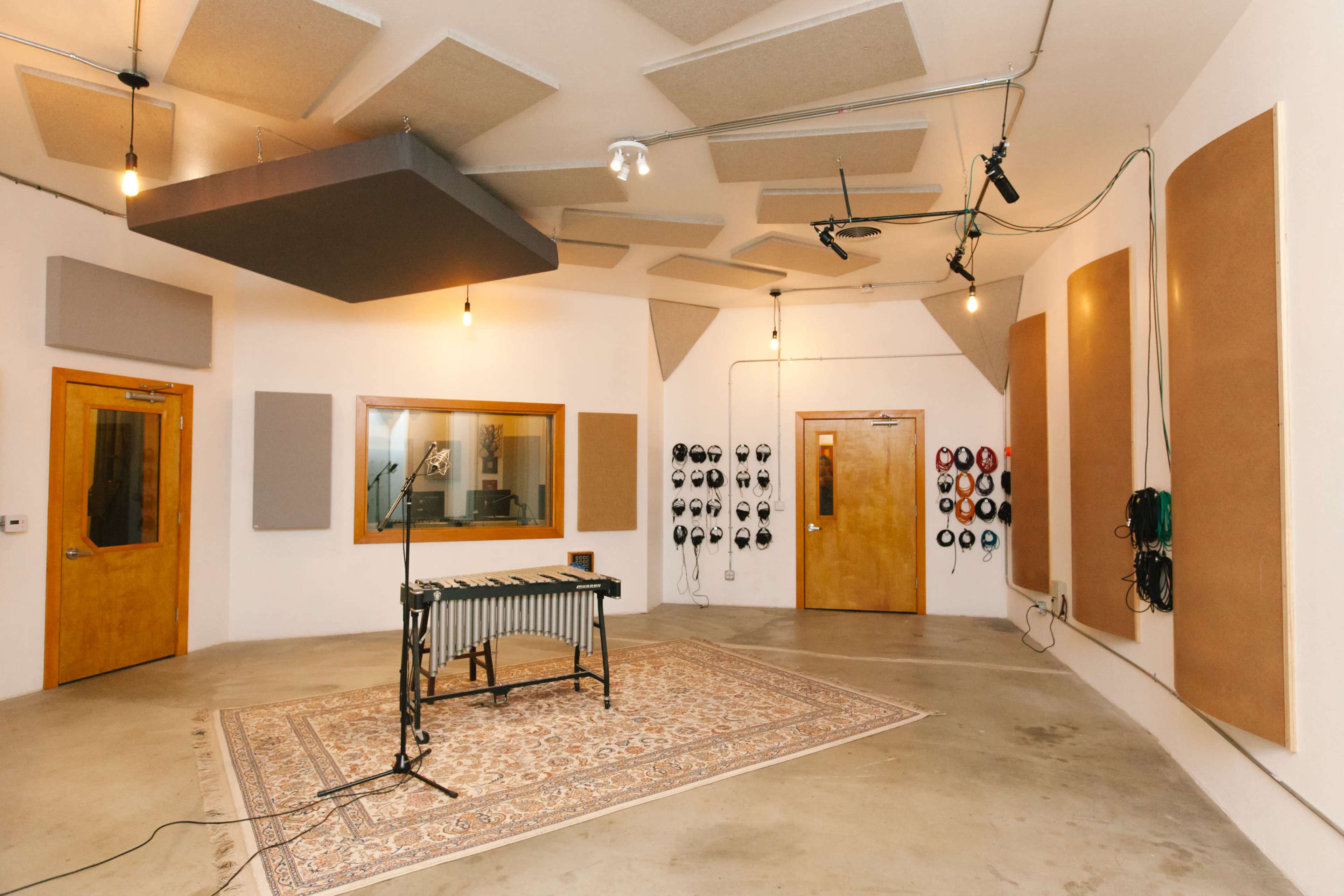 A music recording studio with a xylophone set in the center, surrounded by soundproof panels and multiple doors.
