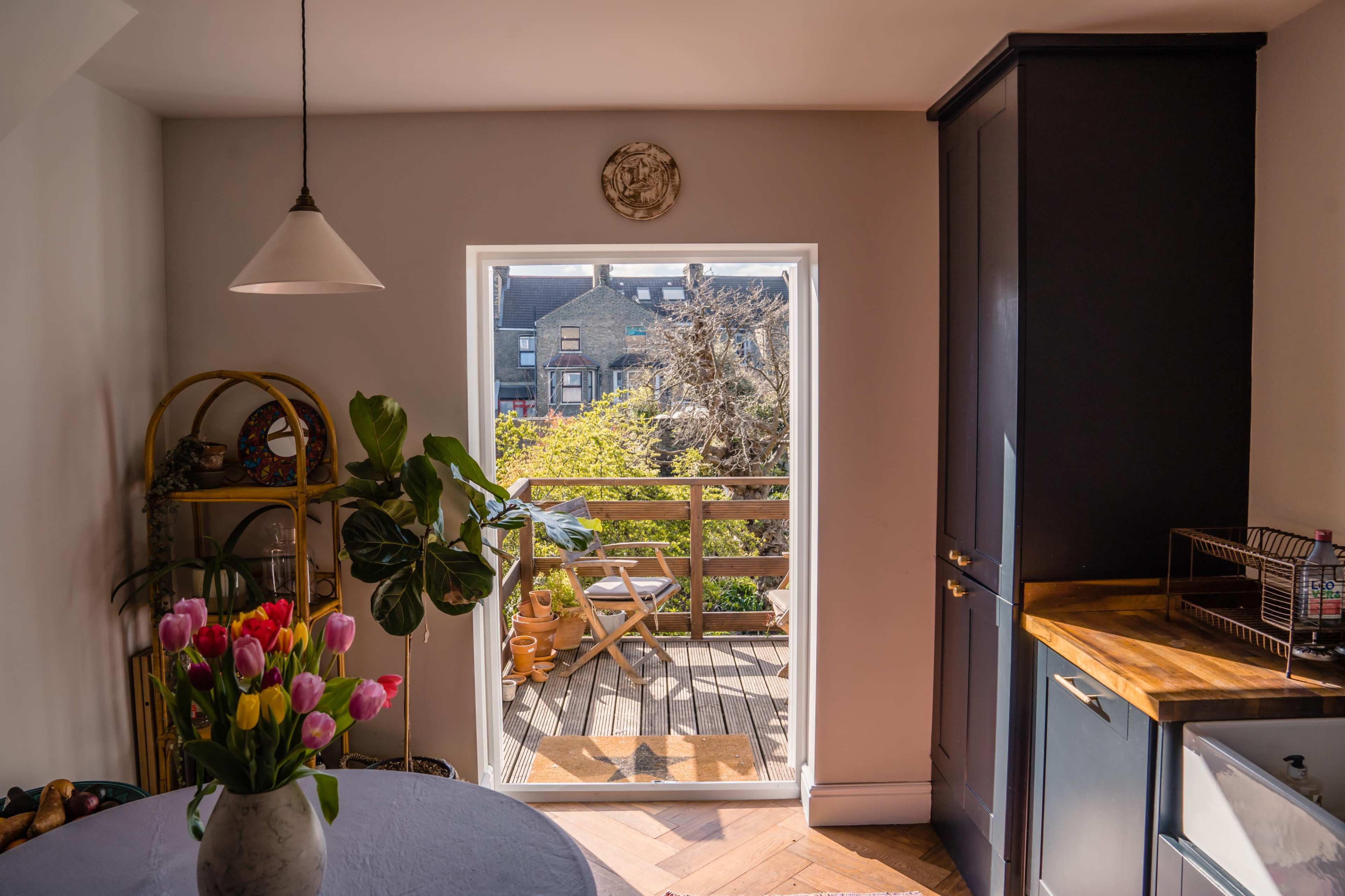 A bright kitchen features a doorway leading to a terrace with outdoor seating and a garden.