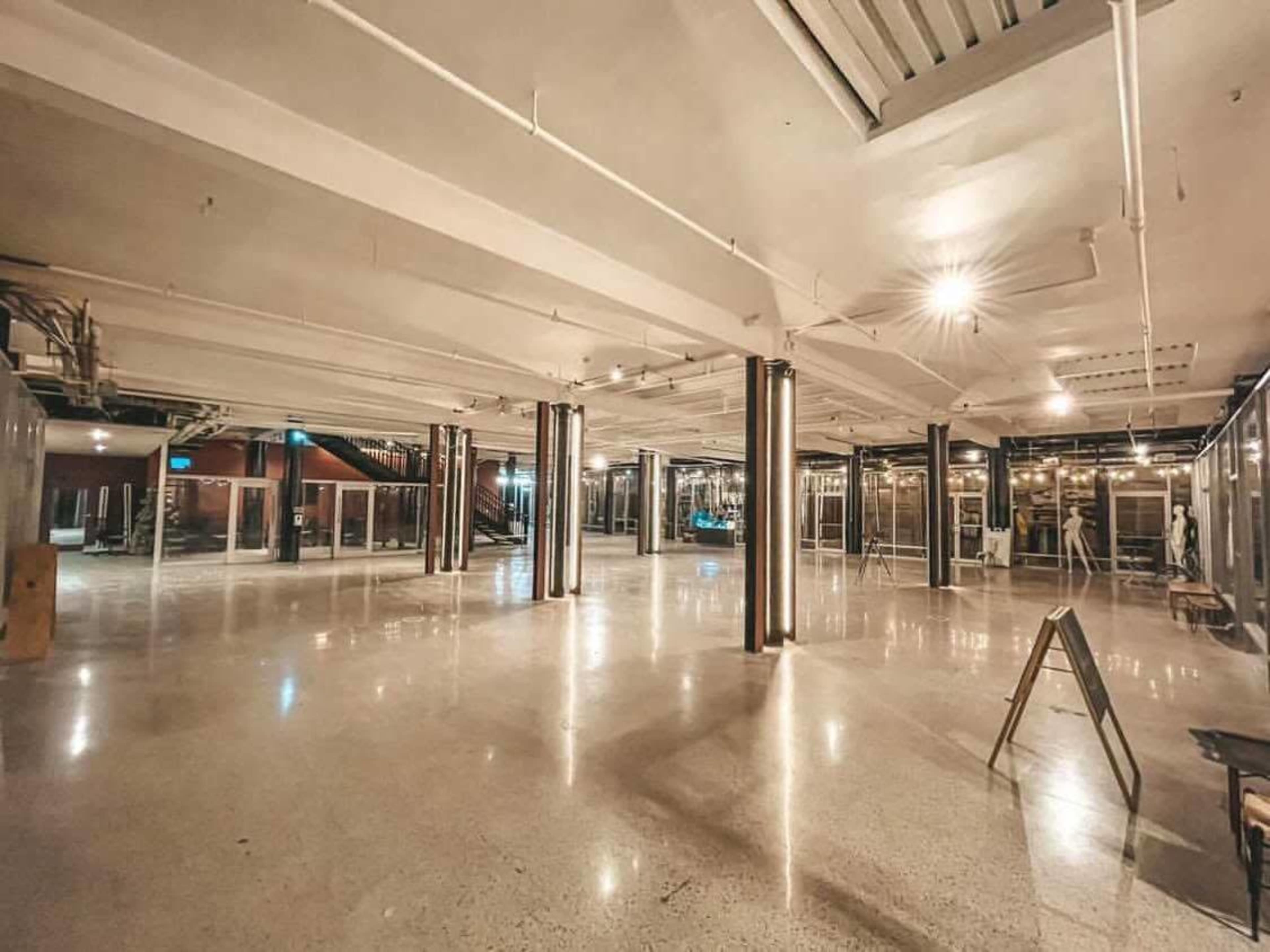 A spacious, empty indoor area with polished concrete floors and metallic columns supporting the ceiling.