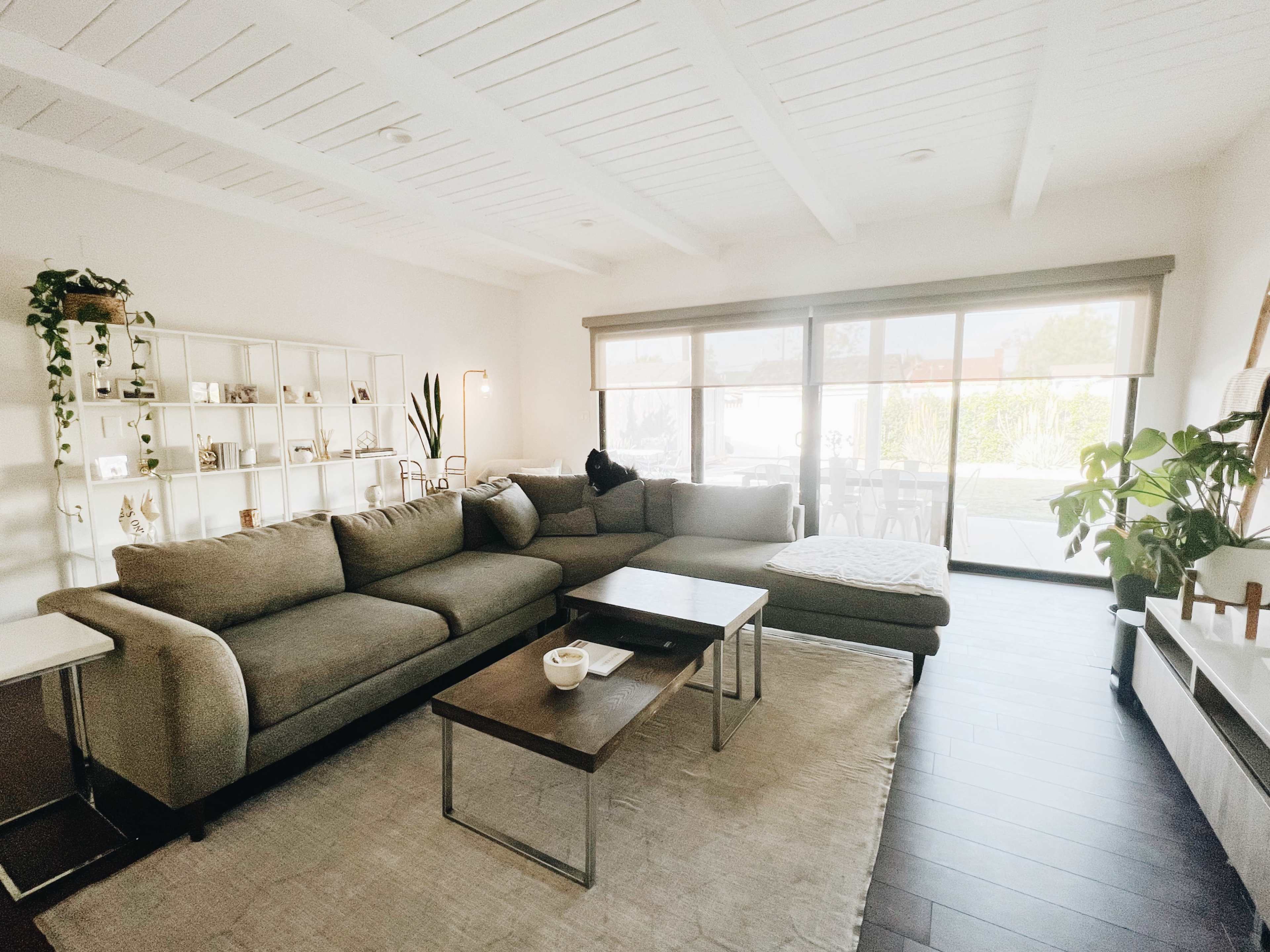 A living room featuring a large sectional sofa, a coffee table, and a view of an outdoor space through sliding glass doors.