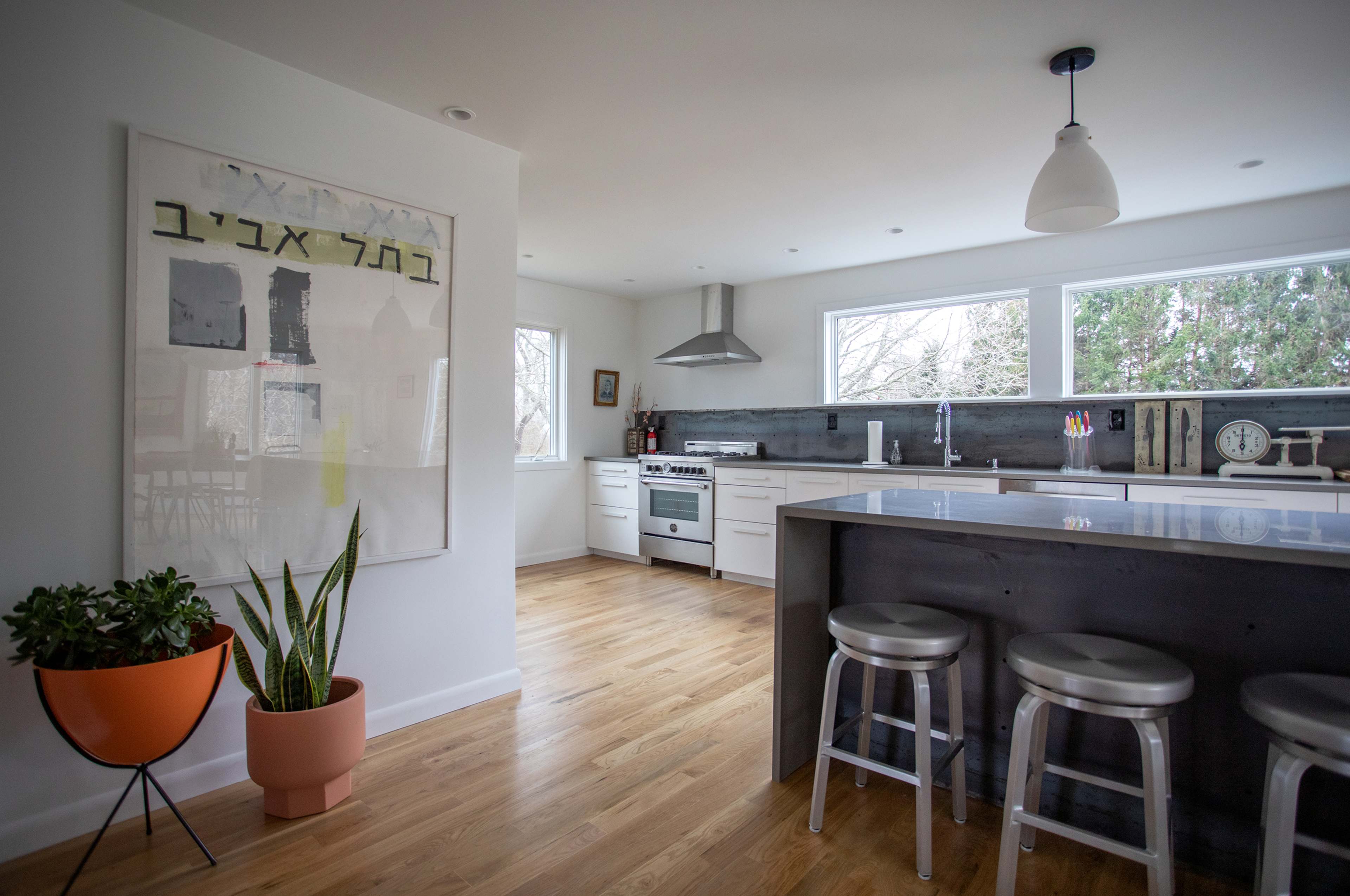 A modern kitchen with stainless steel appliances, a central island with bar stools, and large windows letting in natural light.