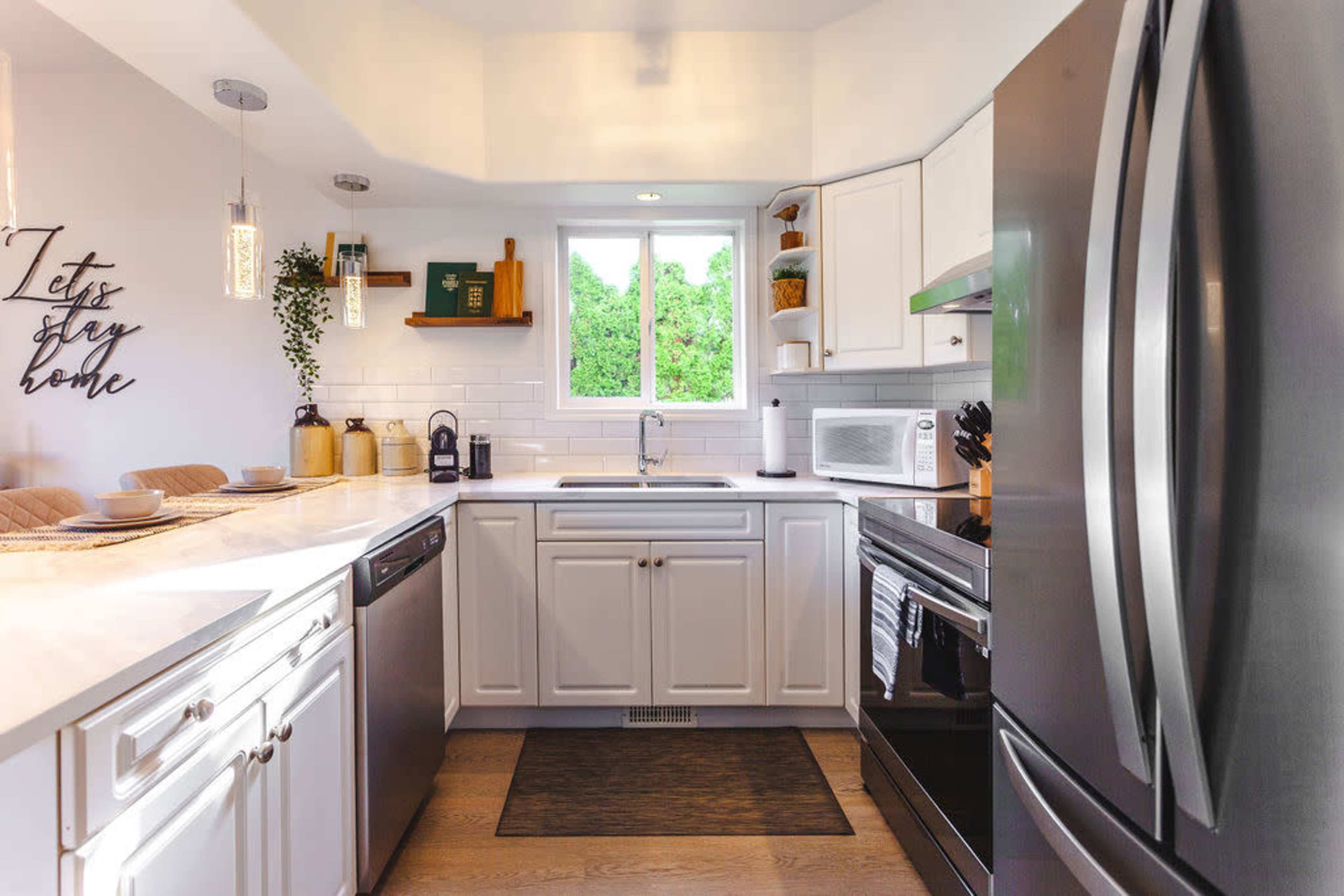 A kitchen featuring white cabinets, stainless steel appliances, and a window overlooking greenery.