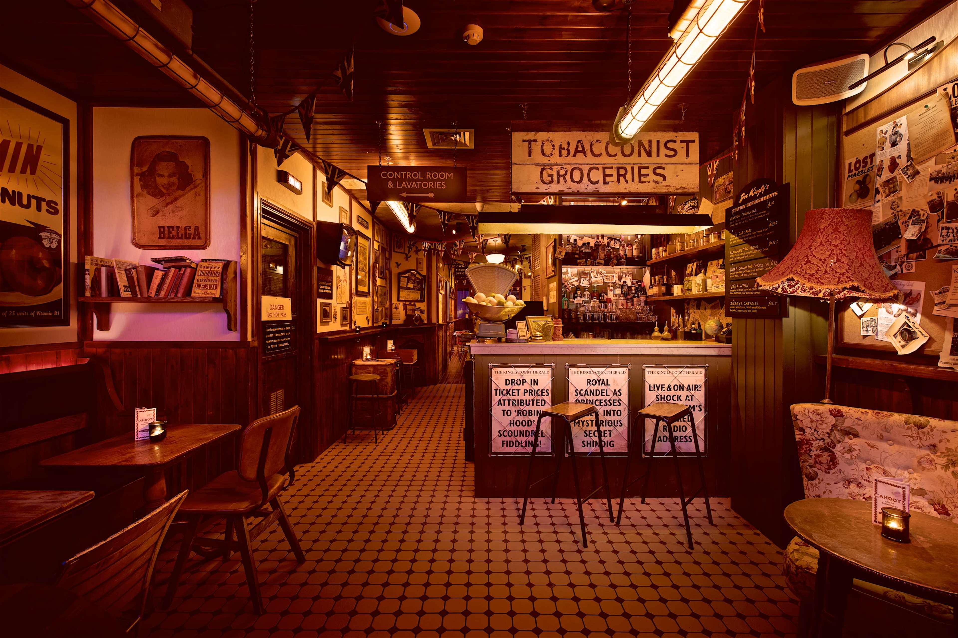 A vintage-style bar with wooden walls, a counter displaying various items, and tables in a warmly lit atmosphere.