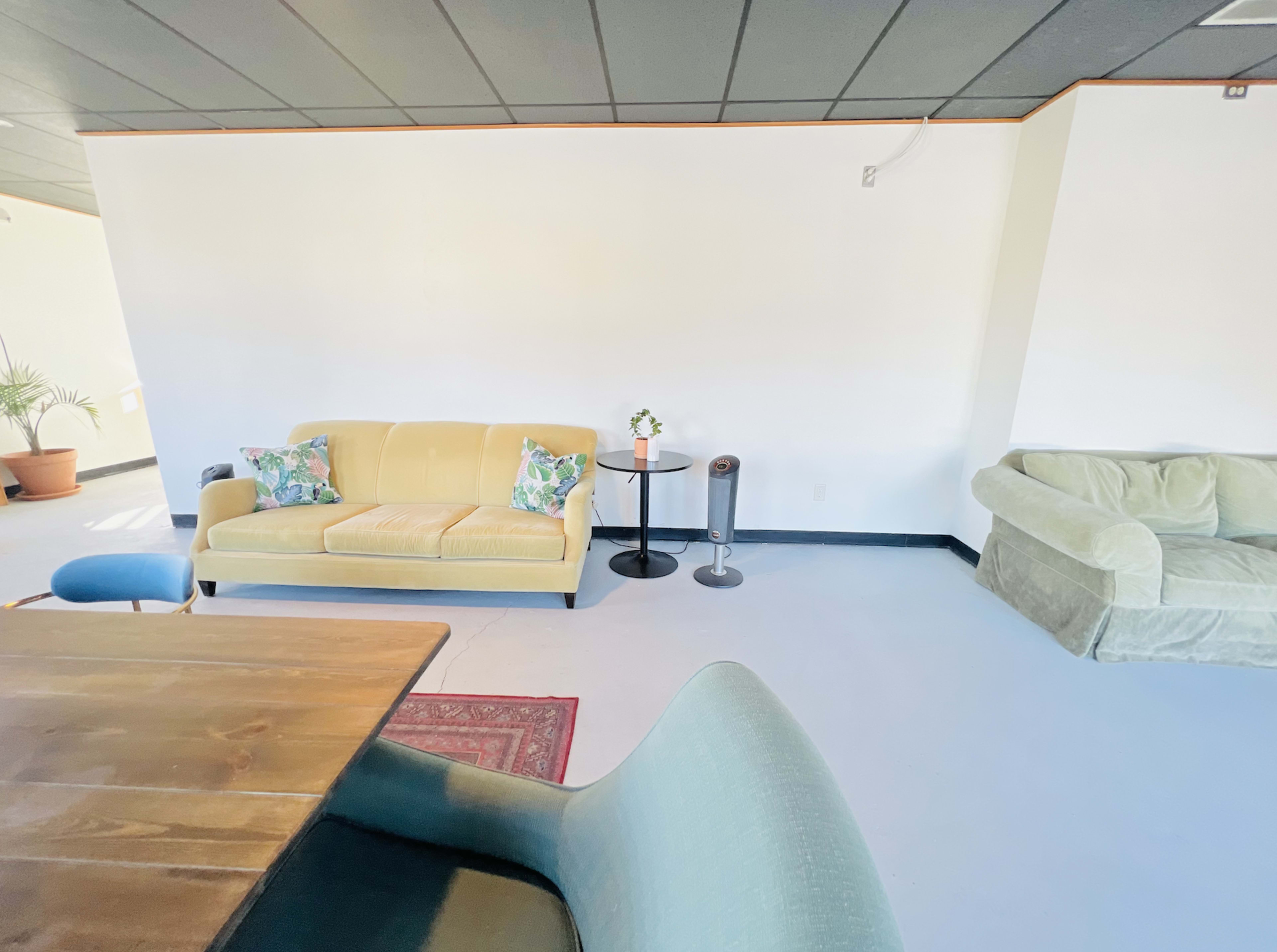 A simple room with a yellow sofa and a green sofa, a table, and decorative items against a white wall.