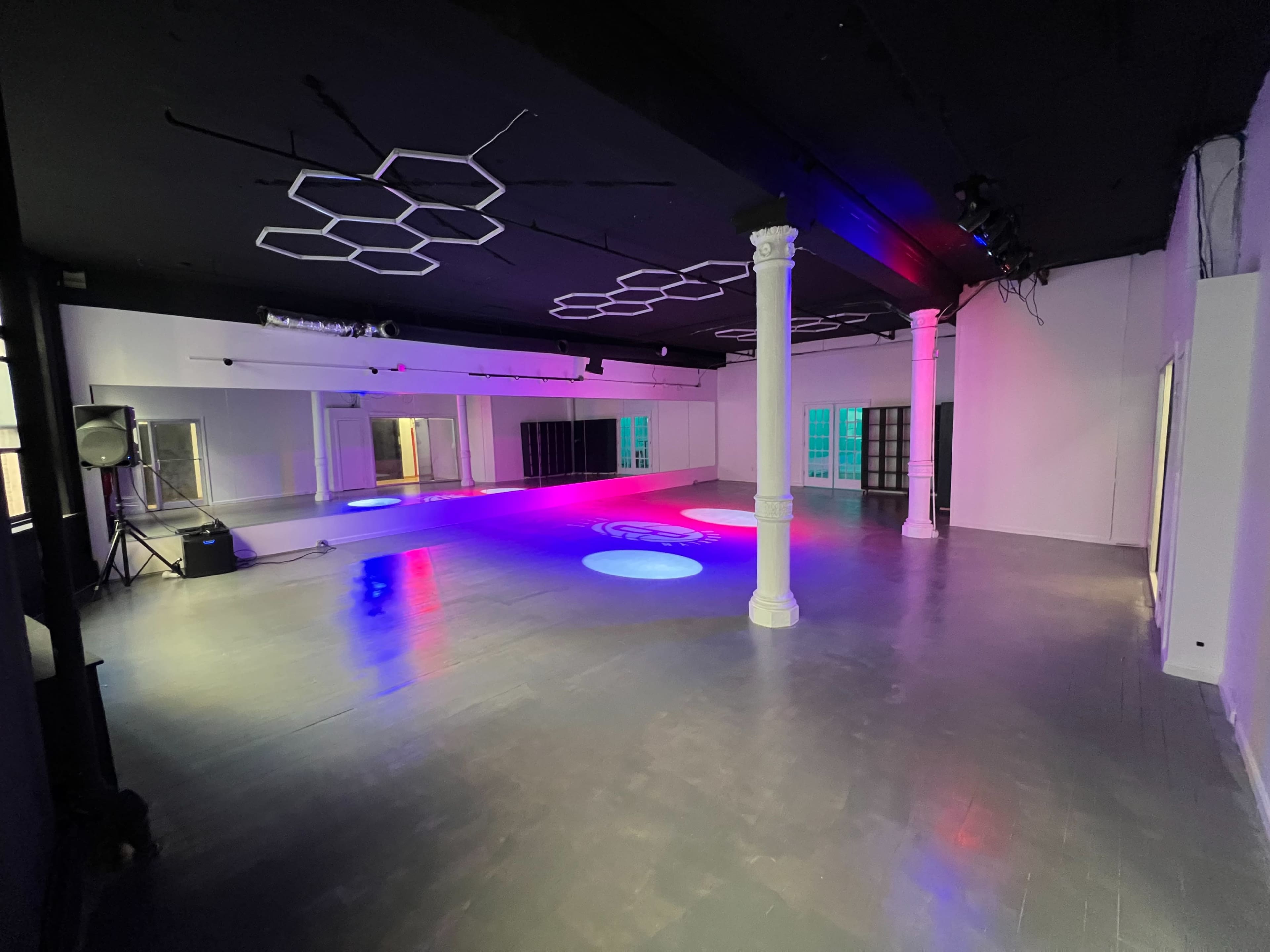 The image shows a spacious, modern indoor venue with polished floors, decorative lighting, and columns.