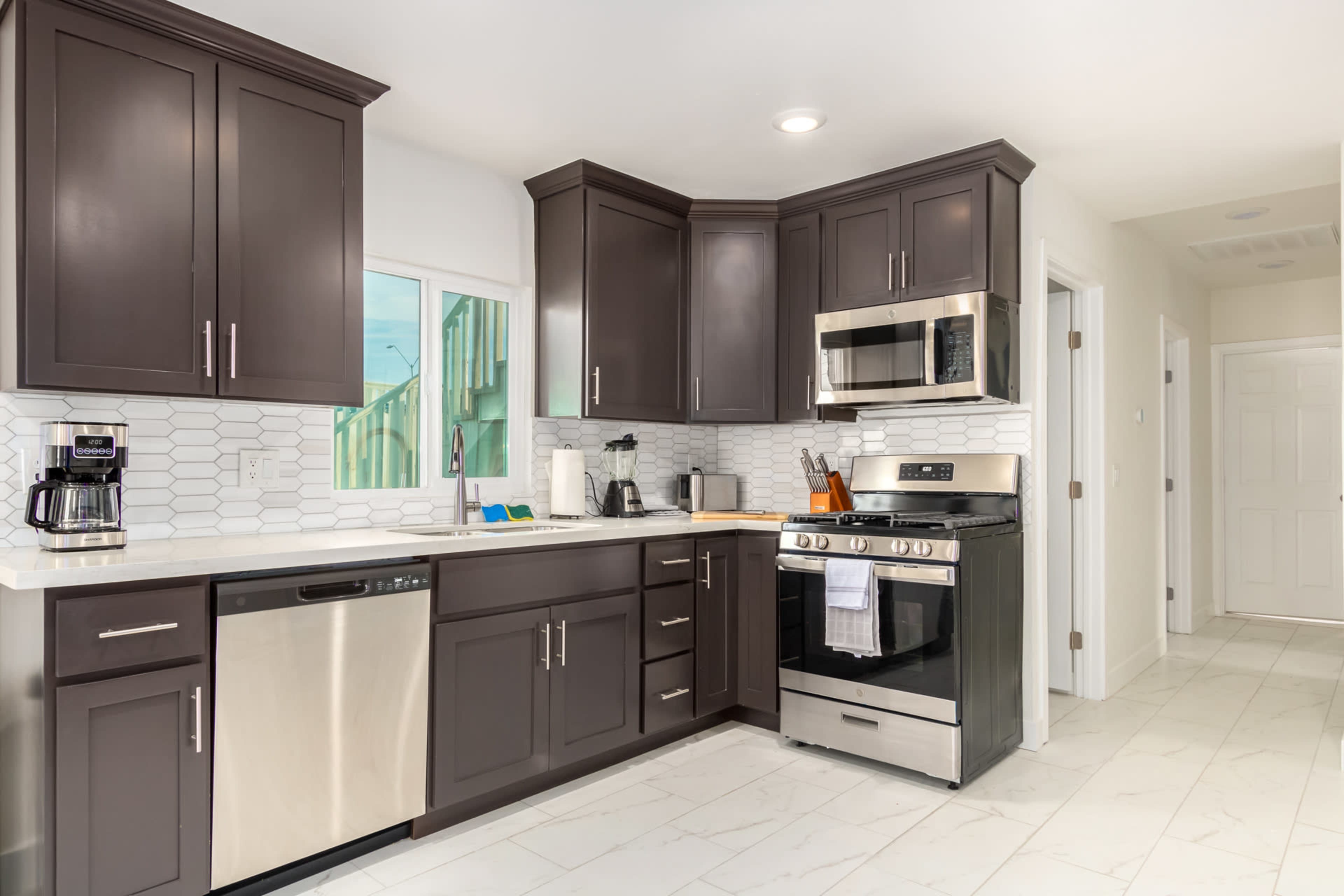 The image shows a modern kitchen featuring dark cabinets, stainless steel appliances, and a white tile backsplash.