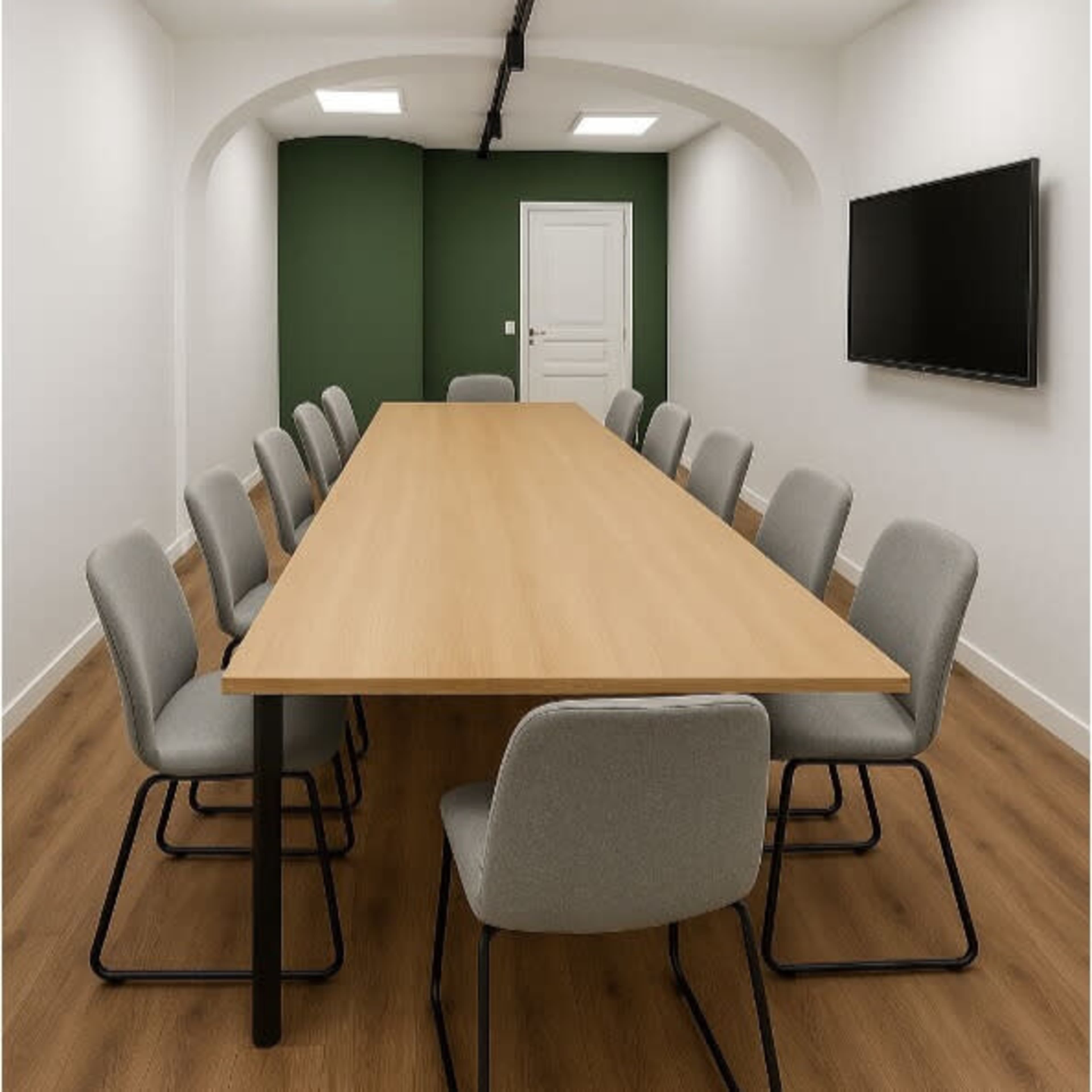 The image shows a modern conference room with a long wooden table surrounded by grey chairs, a green accent wall, and a mounted television on one side.