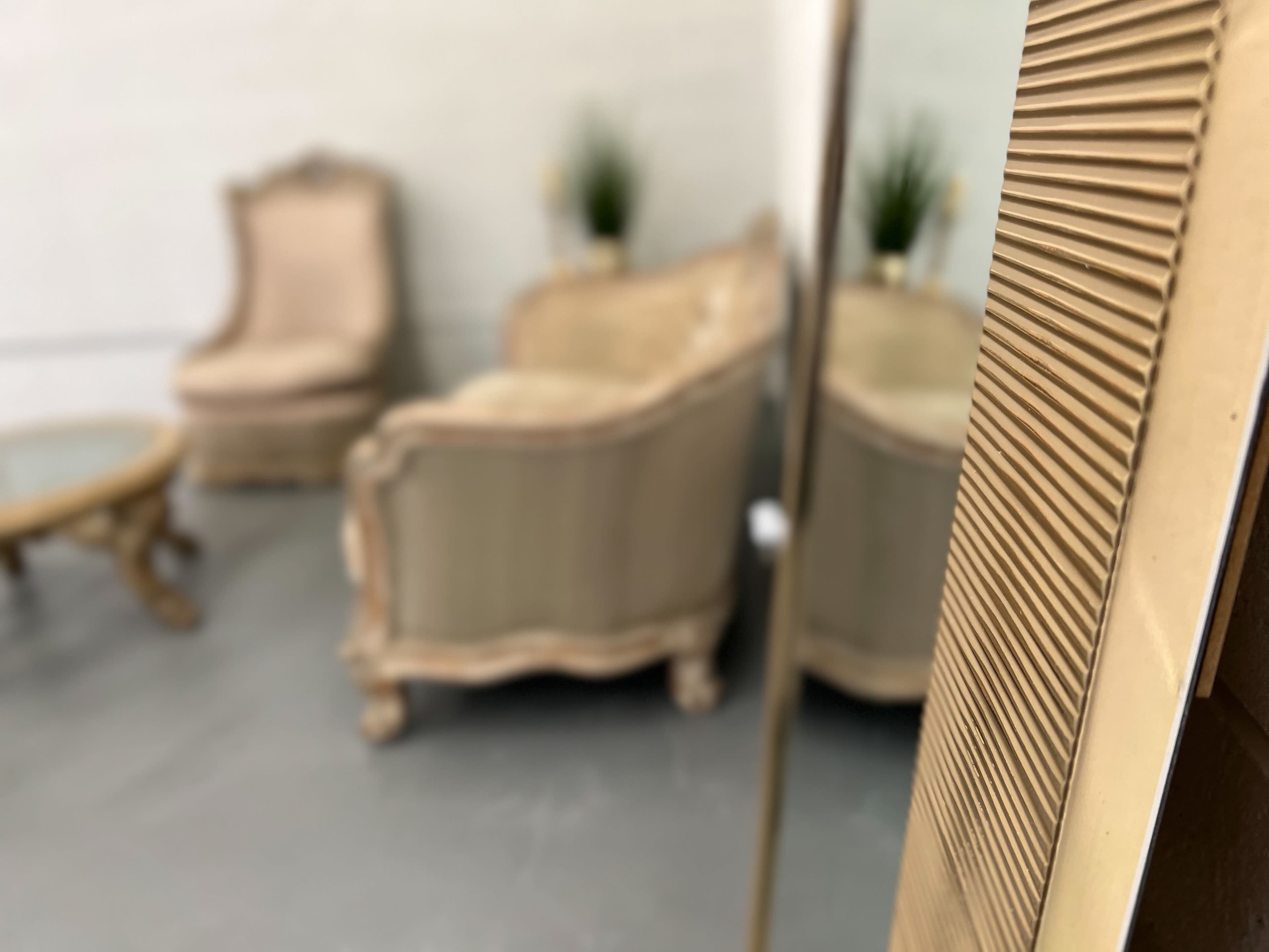 The image shows a seating area with two upholstered chairs and a coffee table, partially obscured by a reflective surface.