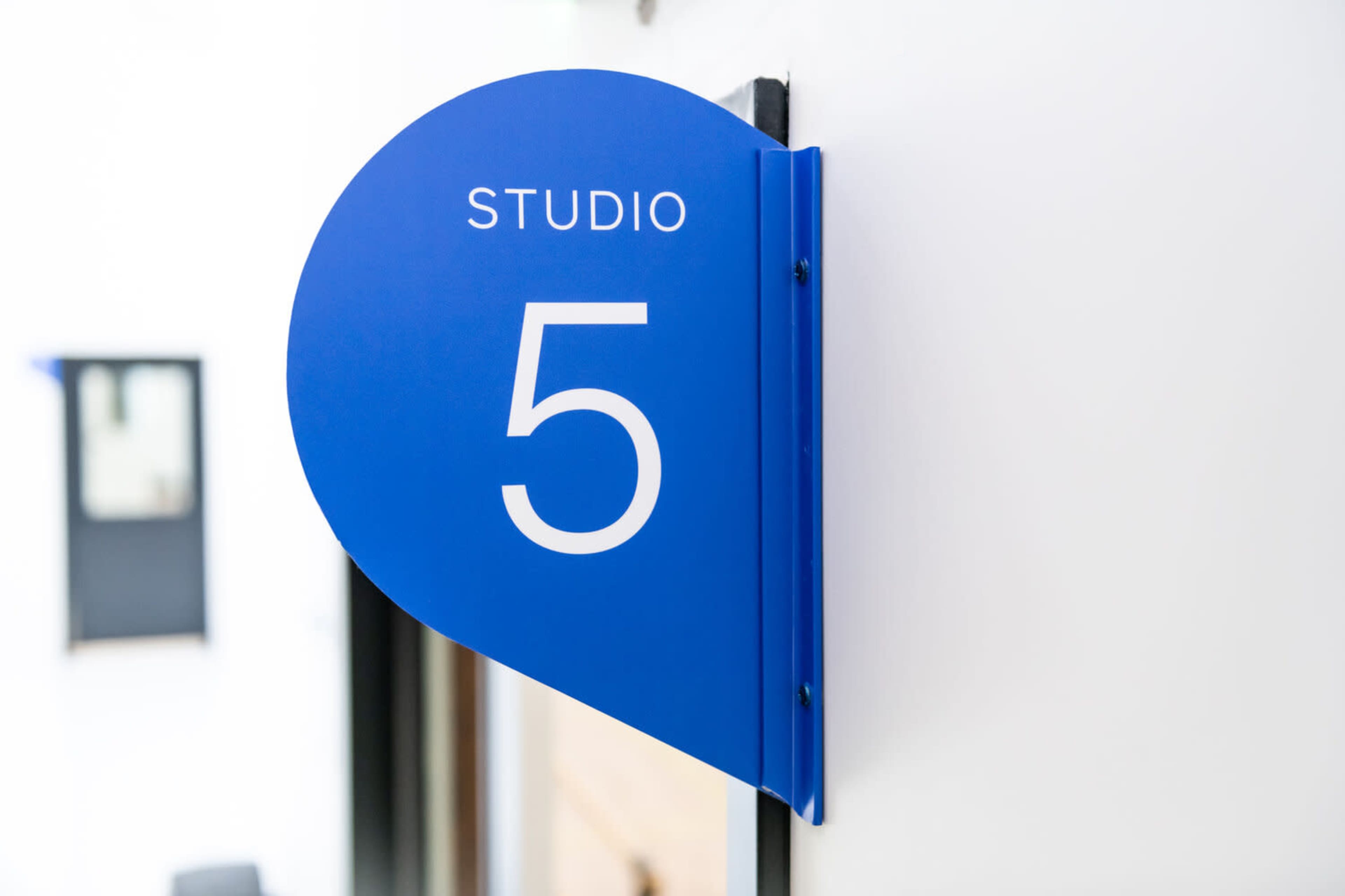 A blue sign displaying the text "STUDIO 5" is mounted on a white wall.