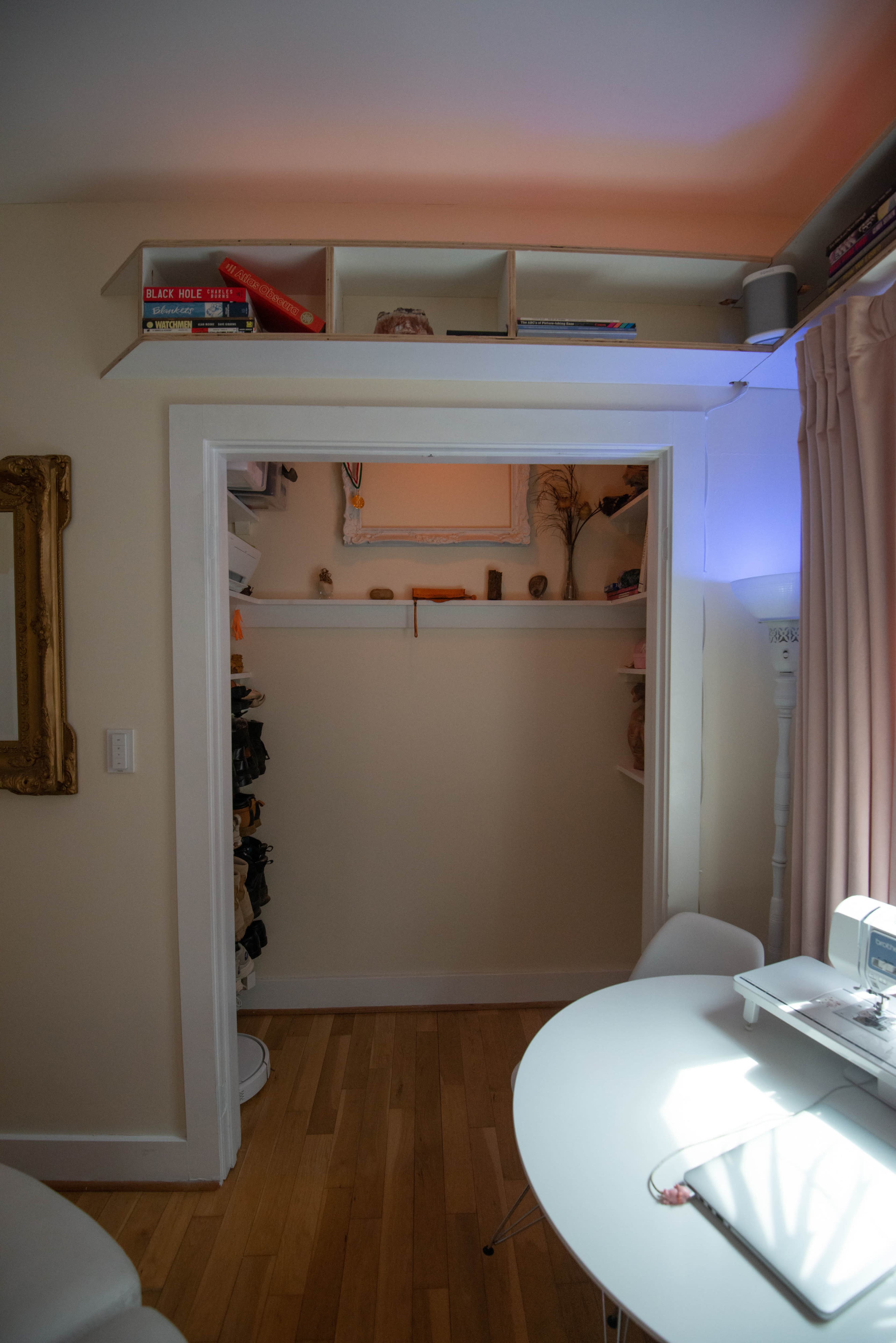 The image shows a small room with a doorway leading to a closet, featuring shelves stocked with various items.