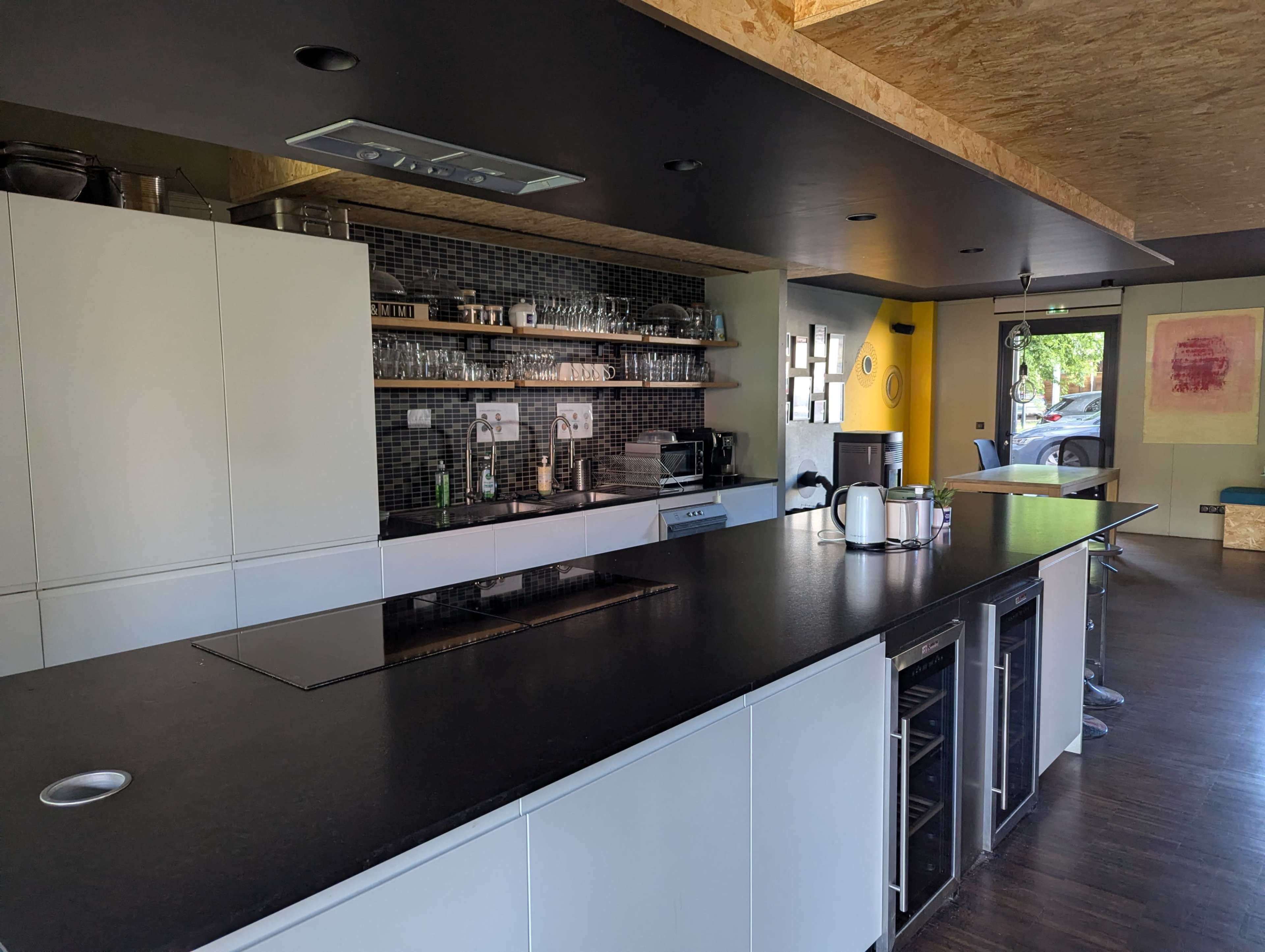 A modern kitchen features a large central island, black countertops, and sleek cabinetry with an open layout.
