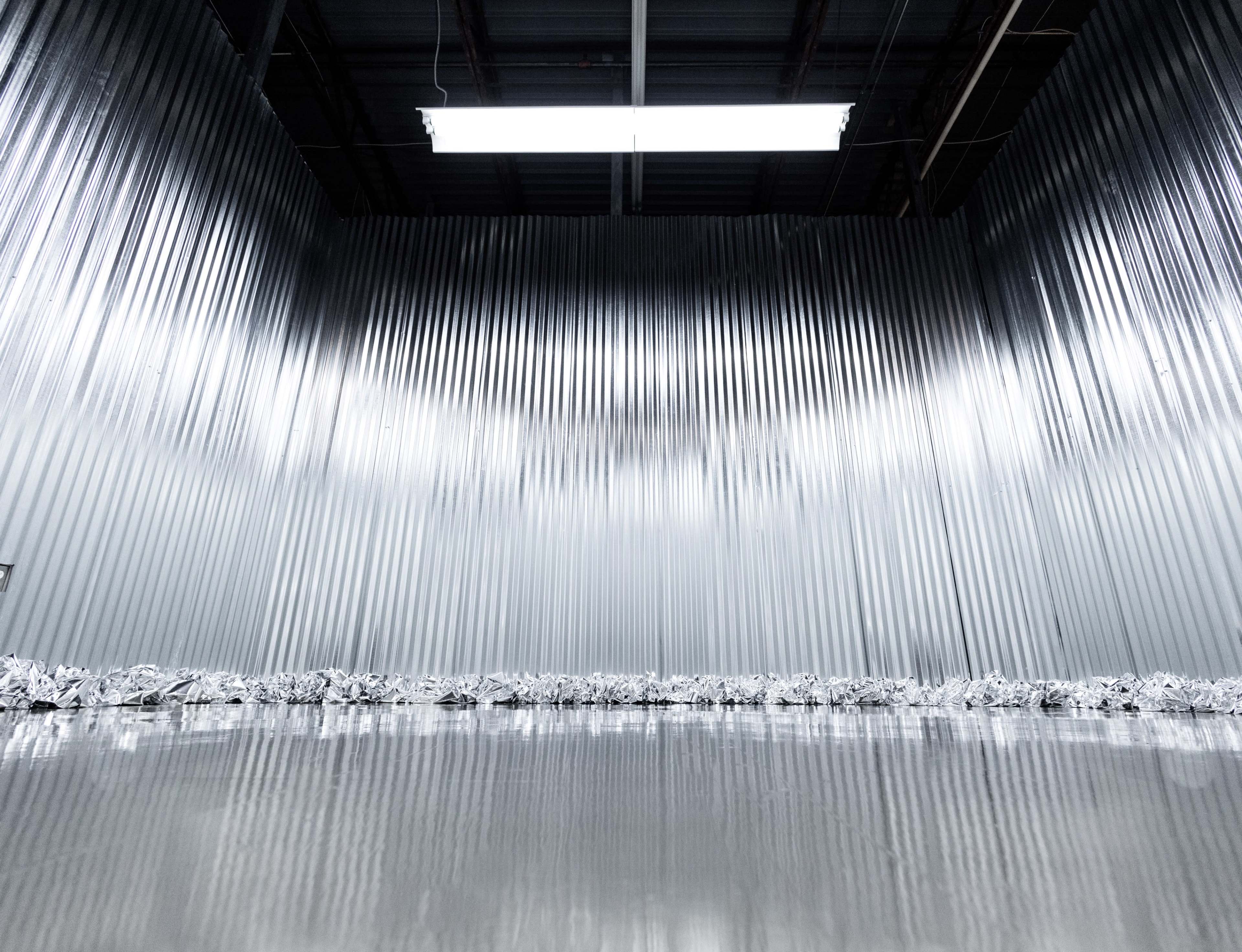 A metallic room with corrugated walls and a shiny, reflective floor.