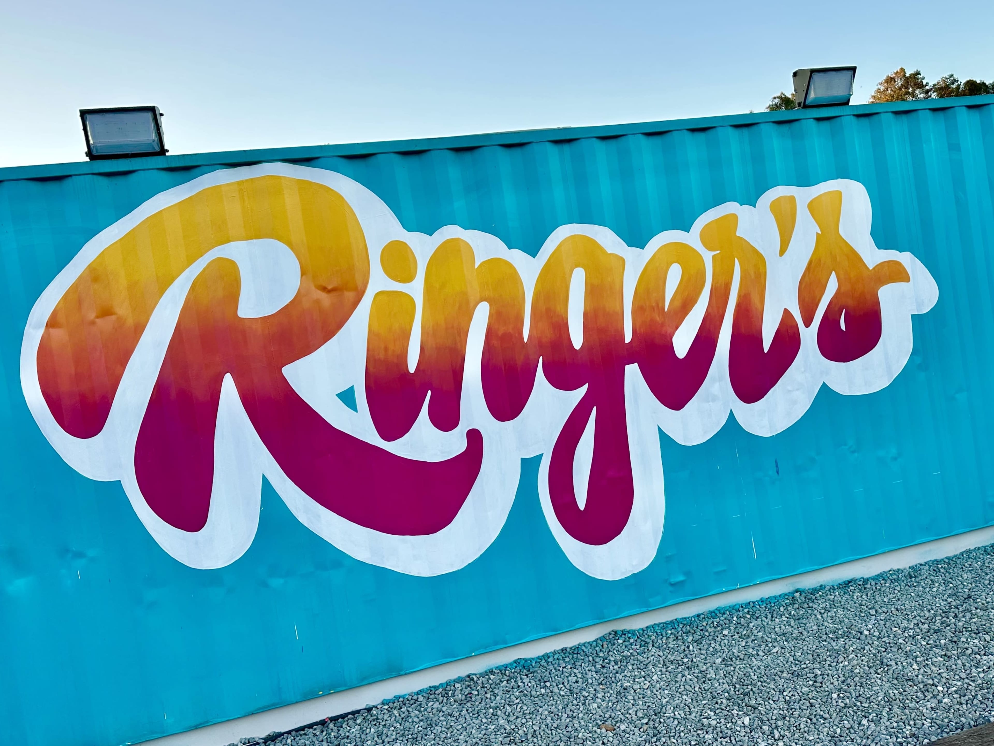 A brightly colored mural of the word "Ringer's" painted on a turquoise shipping container.