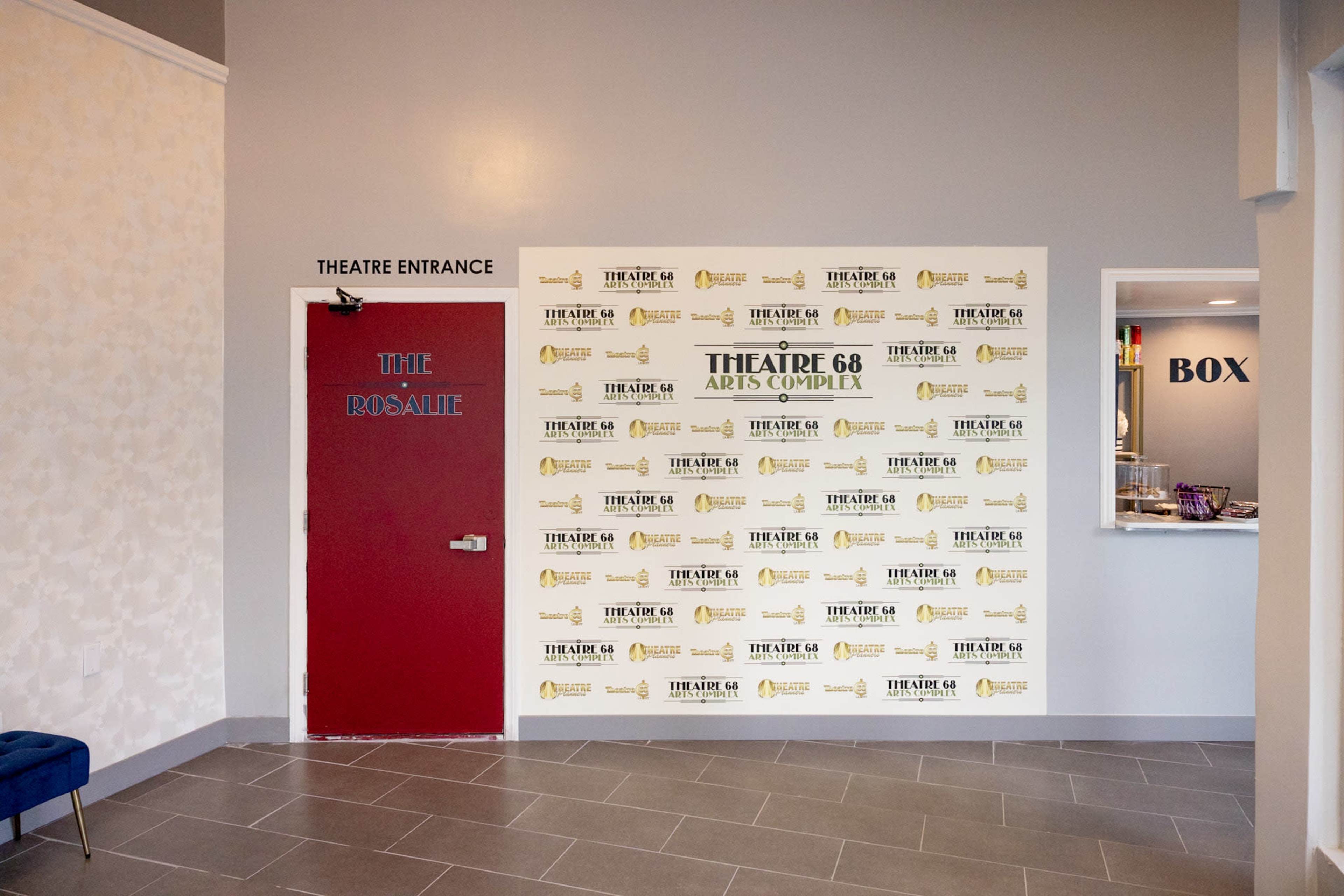 The entrance to Theatre 68 Arts Complex, featuring a red door labeled "THE ROSAIRE" and a wall adorned with event posters and a nearby box office.