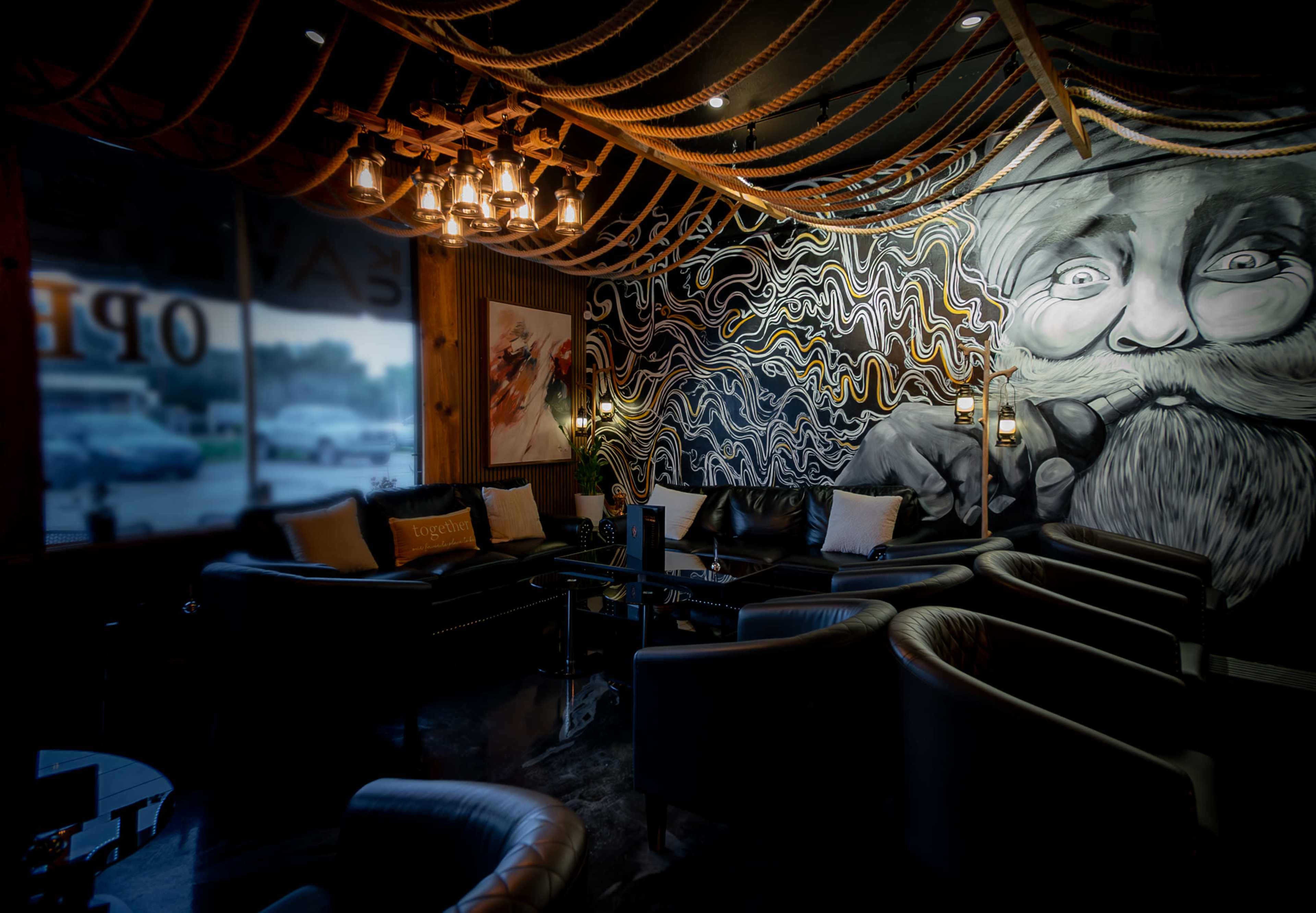 A modern lounge with leather seating, a prominent decorative mural on the wall, and stylish lighting fixtures overhead.