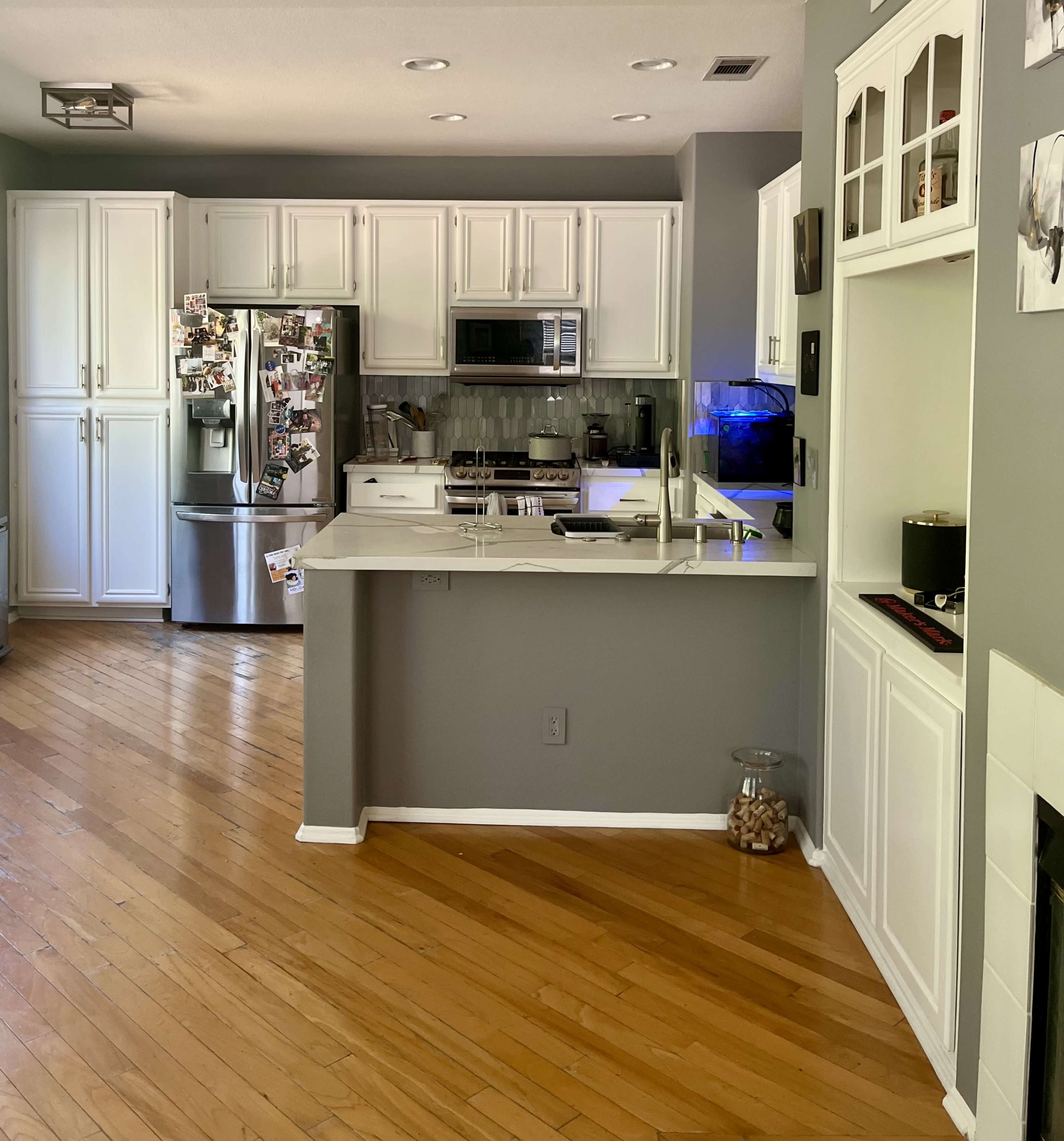 A modern kitchen with white cabinetry, stainless steel appliances, and hardwood flooring.