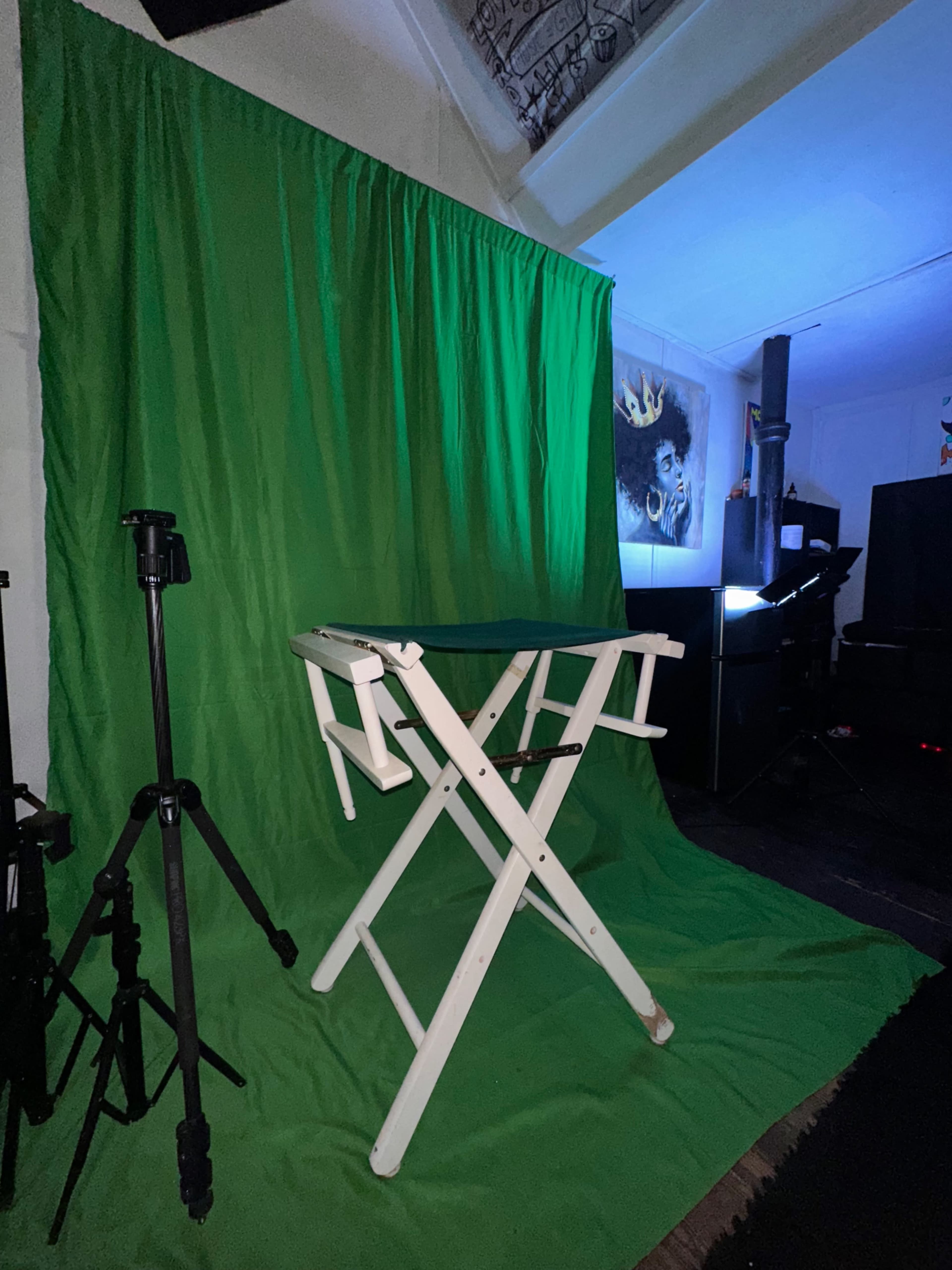 The image shows a green backdrop with a folding chair in front of it, surrounded by photography equipment.