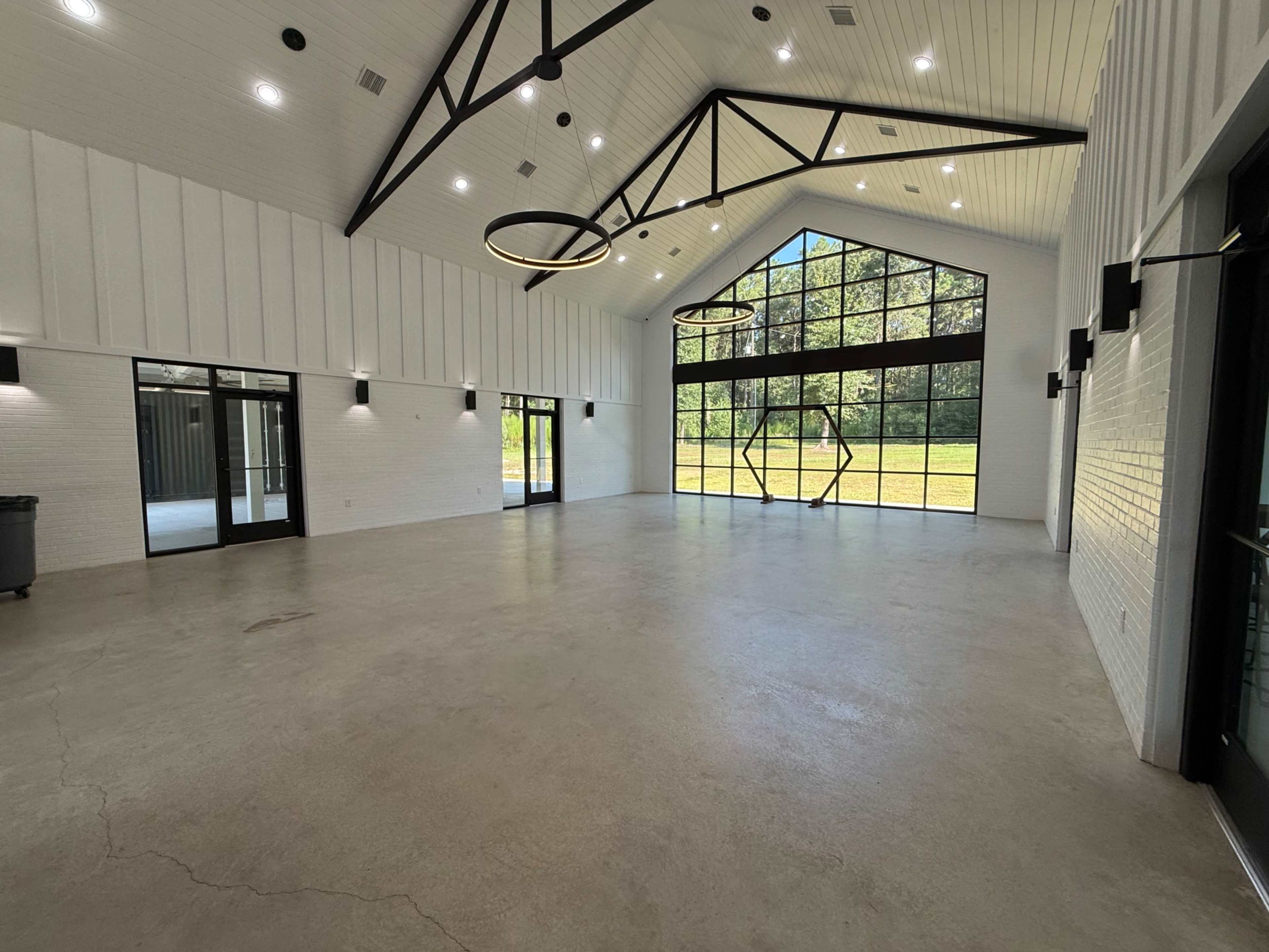 The image shows a large, bright indoor space with high ceilings, large windows, and a concrete floor.