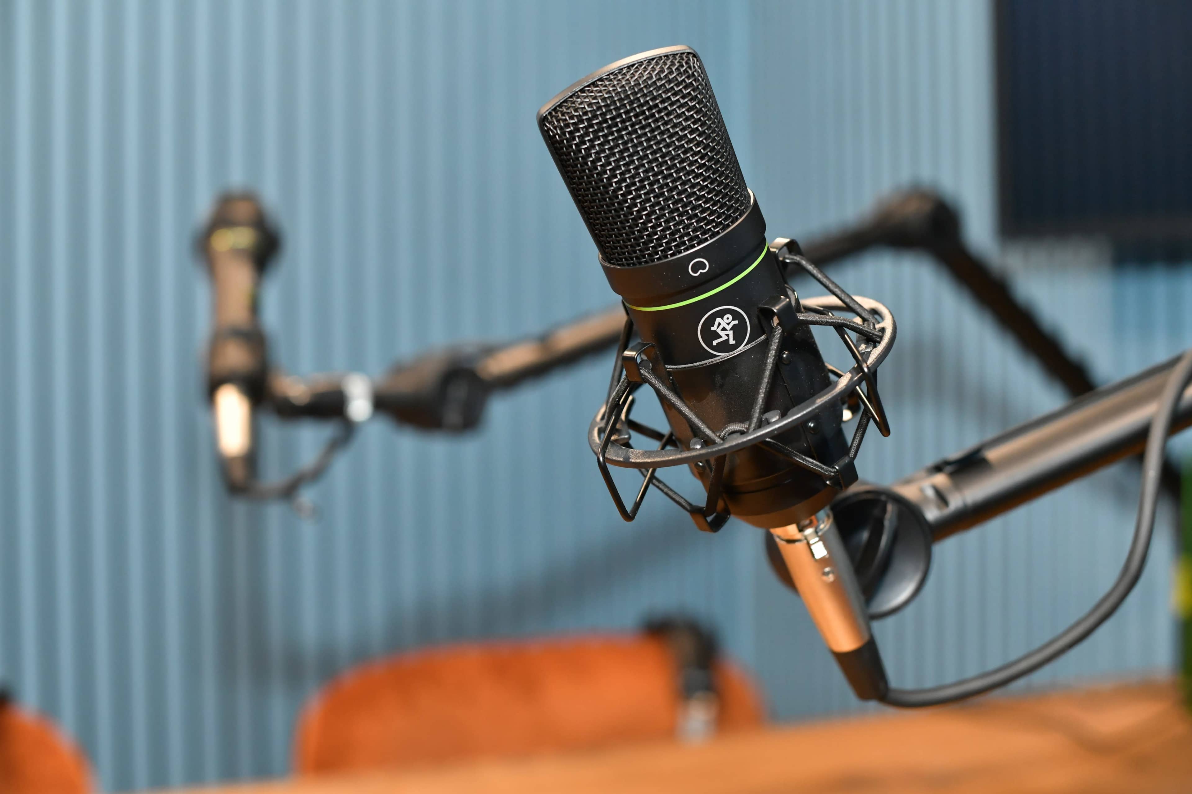 A close-up of a microphone mounted on an adjustable arm in a room with blue paneling.