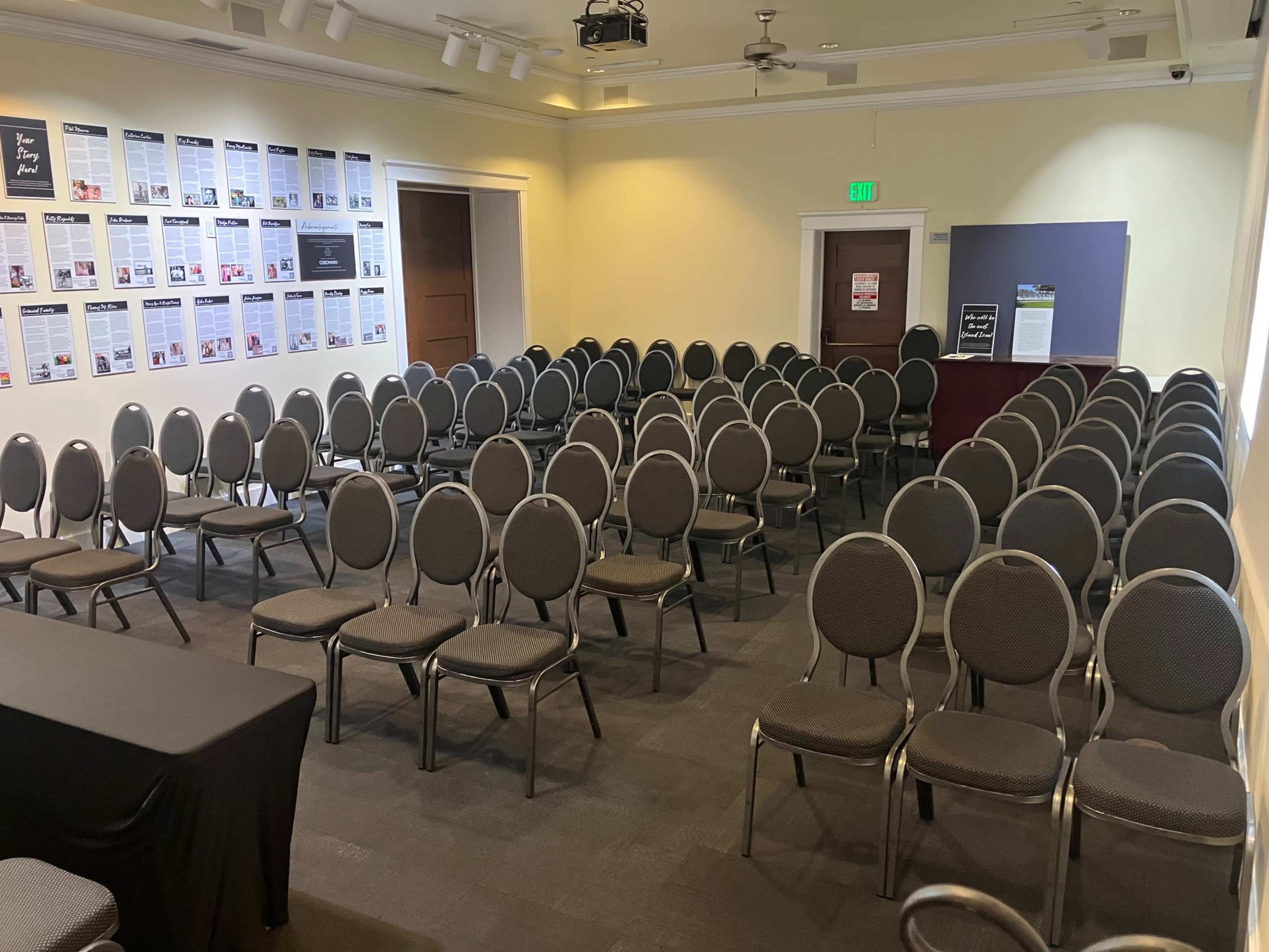 A conference room arranged with multiple rows of circular chairs facing a stage area.