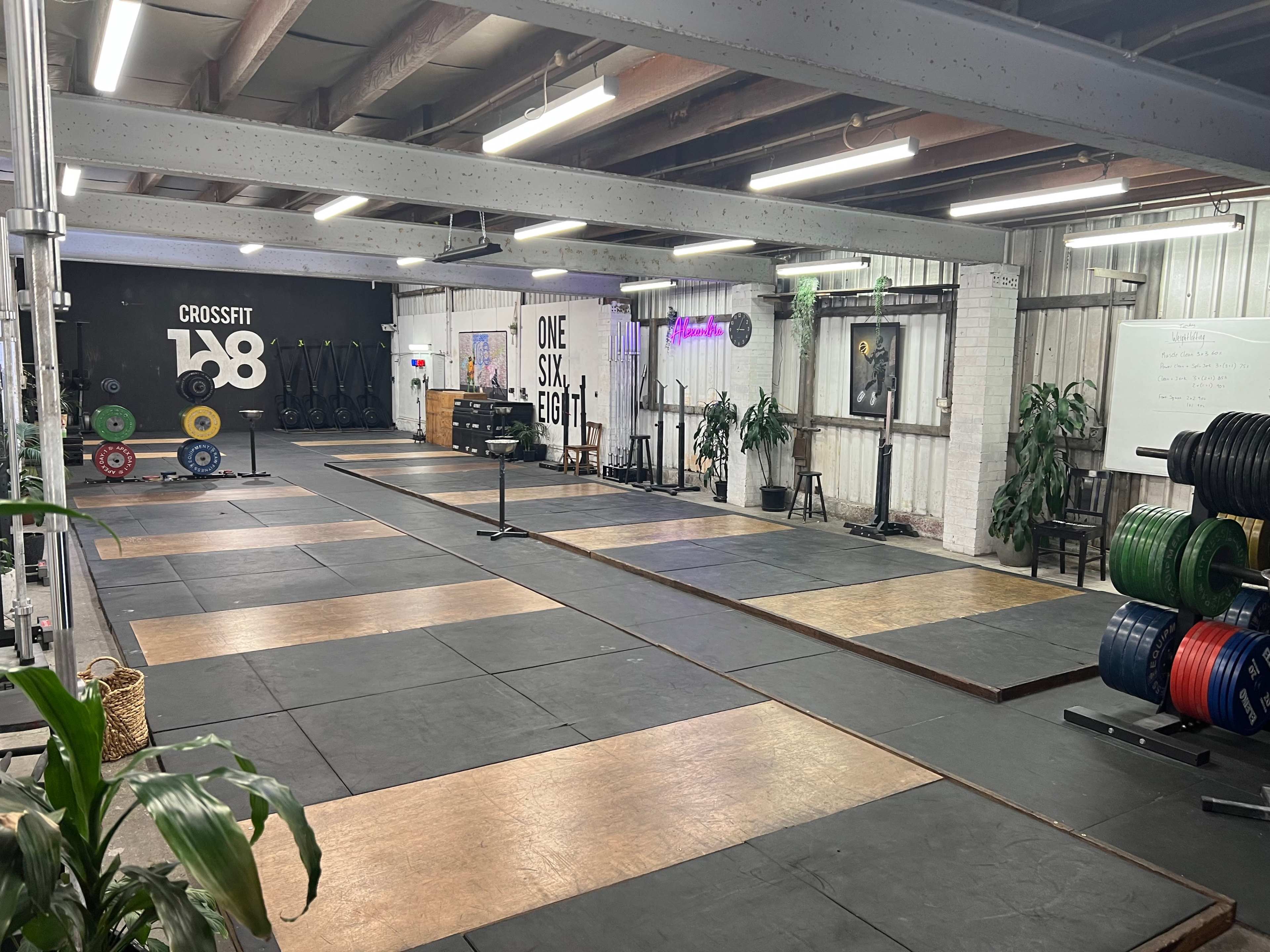 A CrossFit gym with designated lifting areas, weight plates, and equipment arranged neatly on a rubber floor.