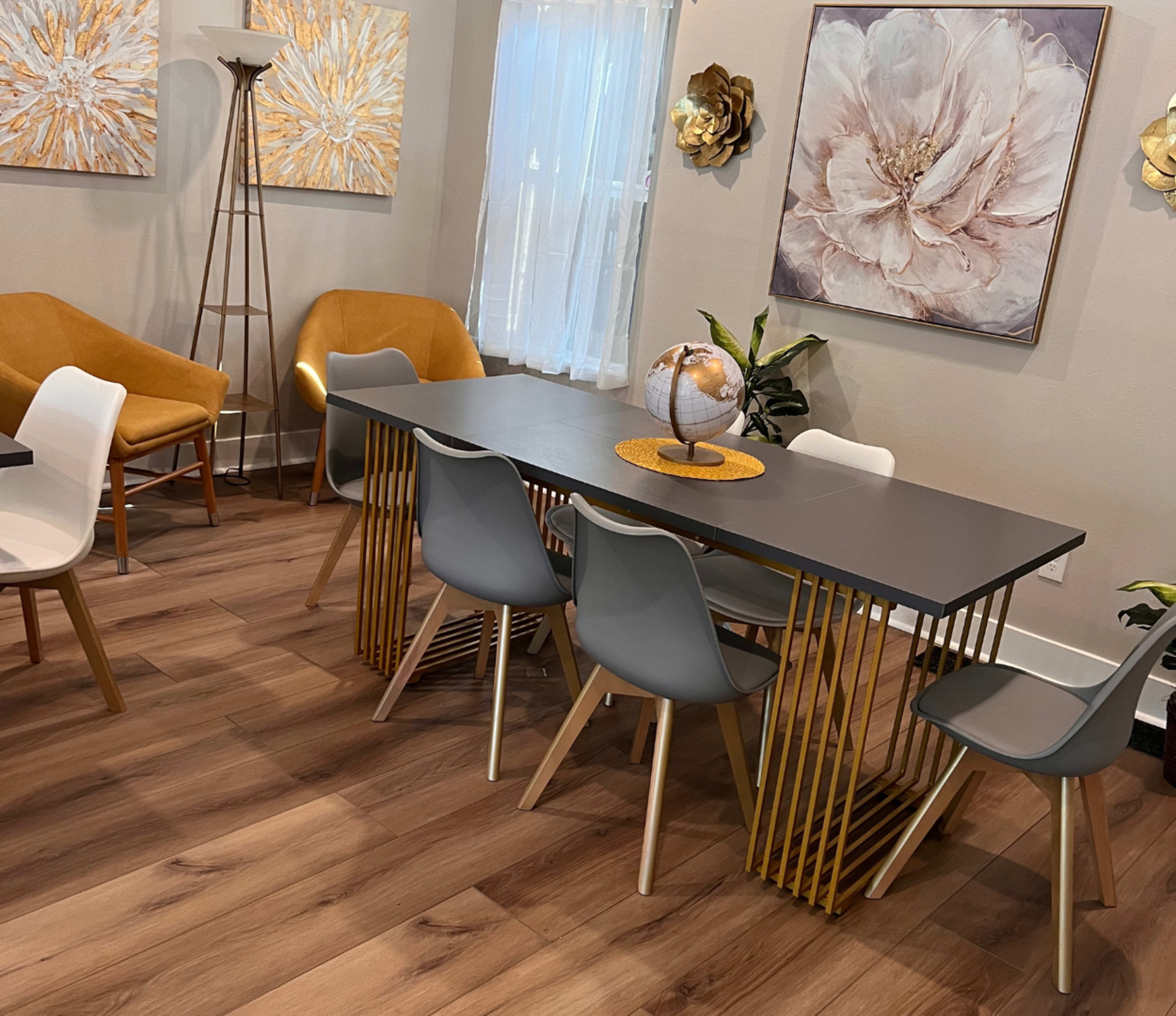 A modern dining area with a sleek table, stylish chairs, and decorative wall art featuring floral designs.