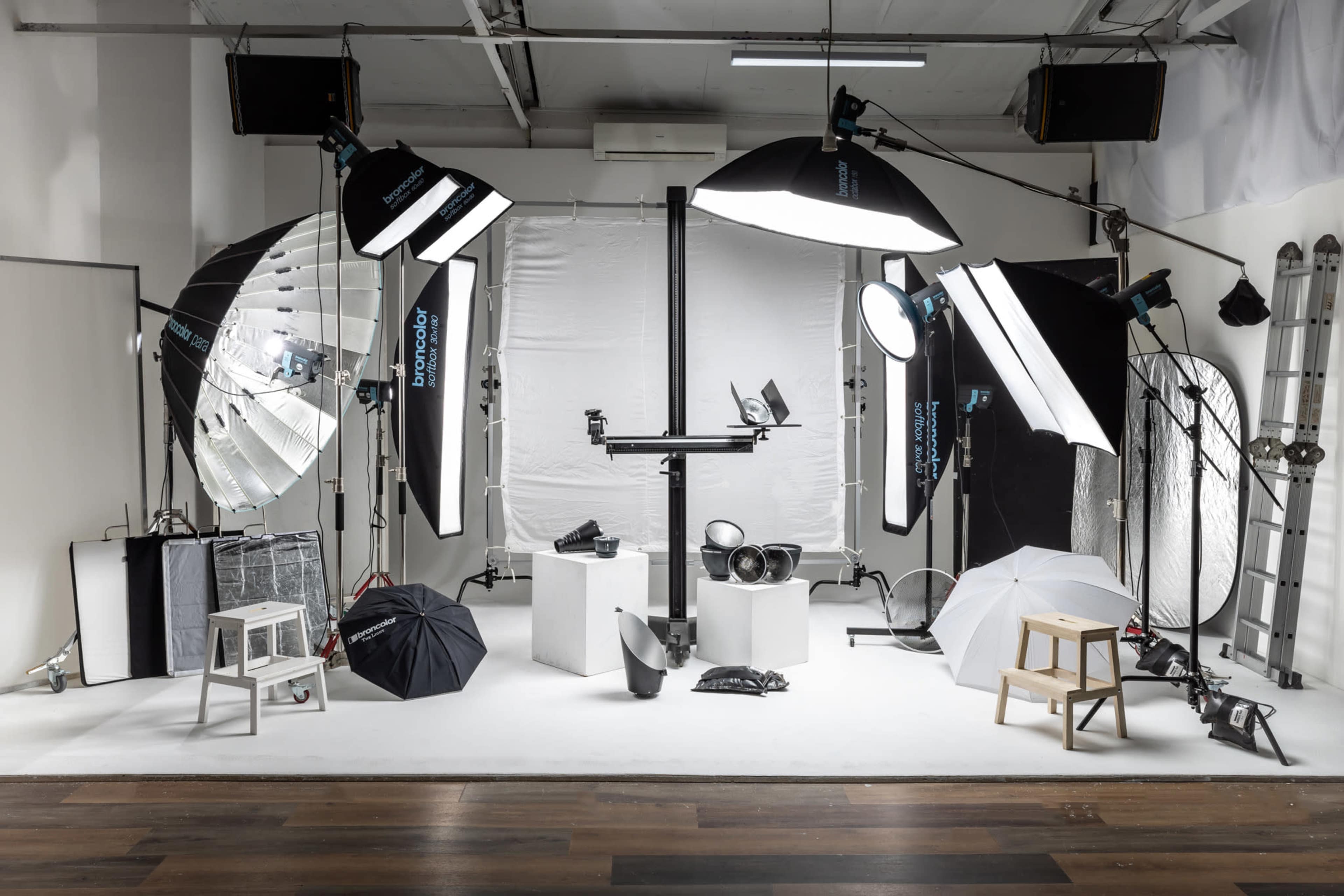 A photography studio equipped with various lighting setups, backdrops, and props arranged on a white floor.