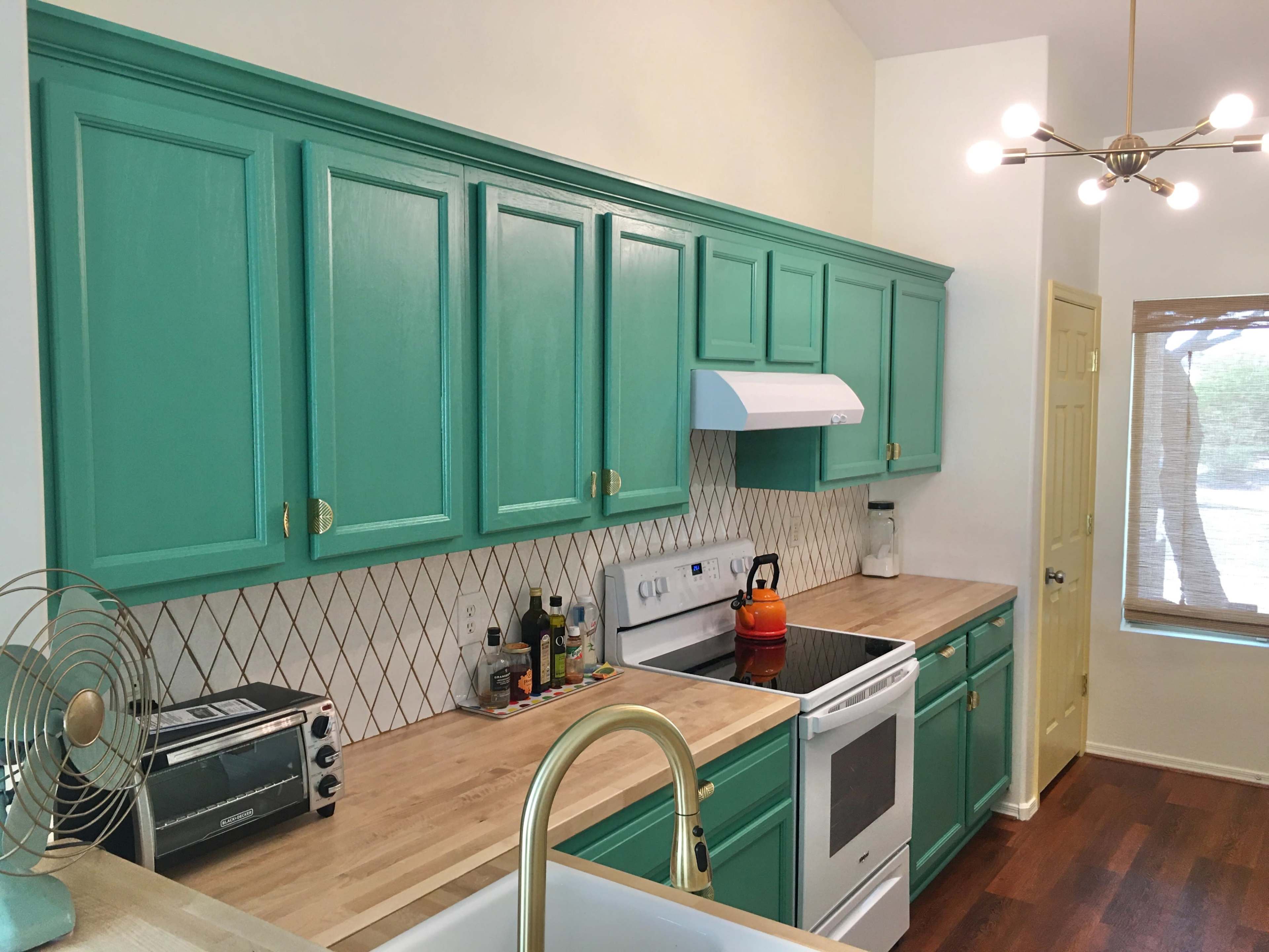 A kitchen with turquoise cabinets, a white oven and range hood, and a wooden countertop.