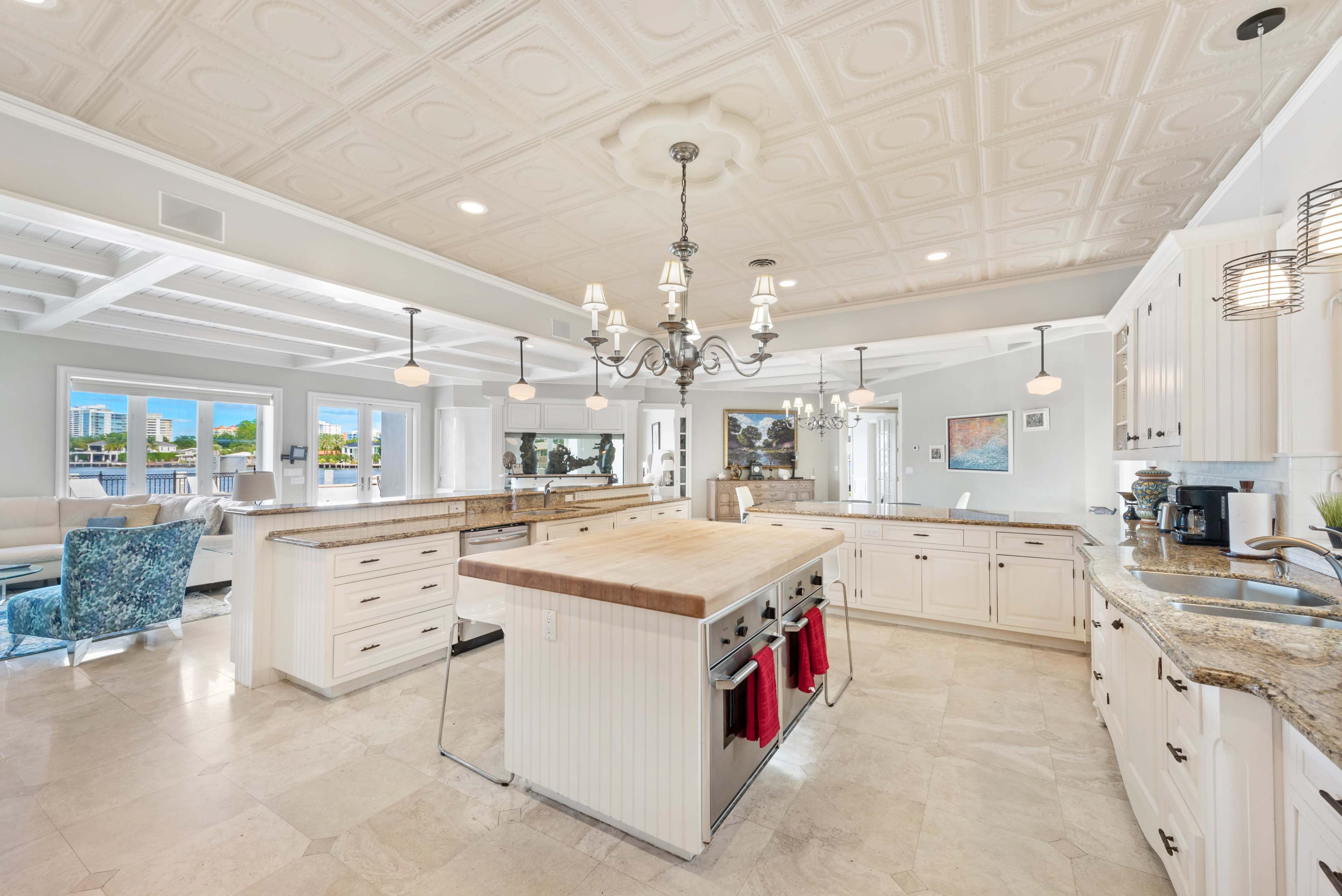 A spacious kitchen features a central island, white cabinetry, and modern appliances, with large windows providing natural light.