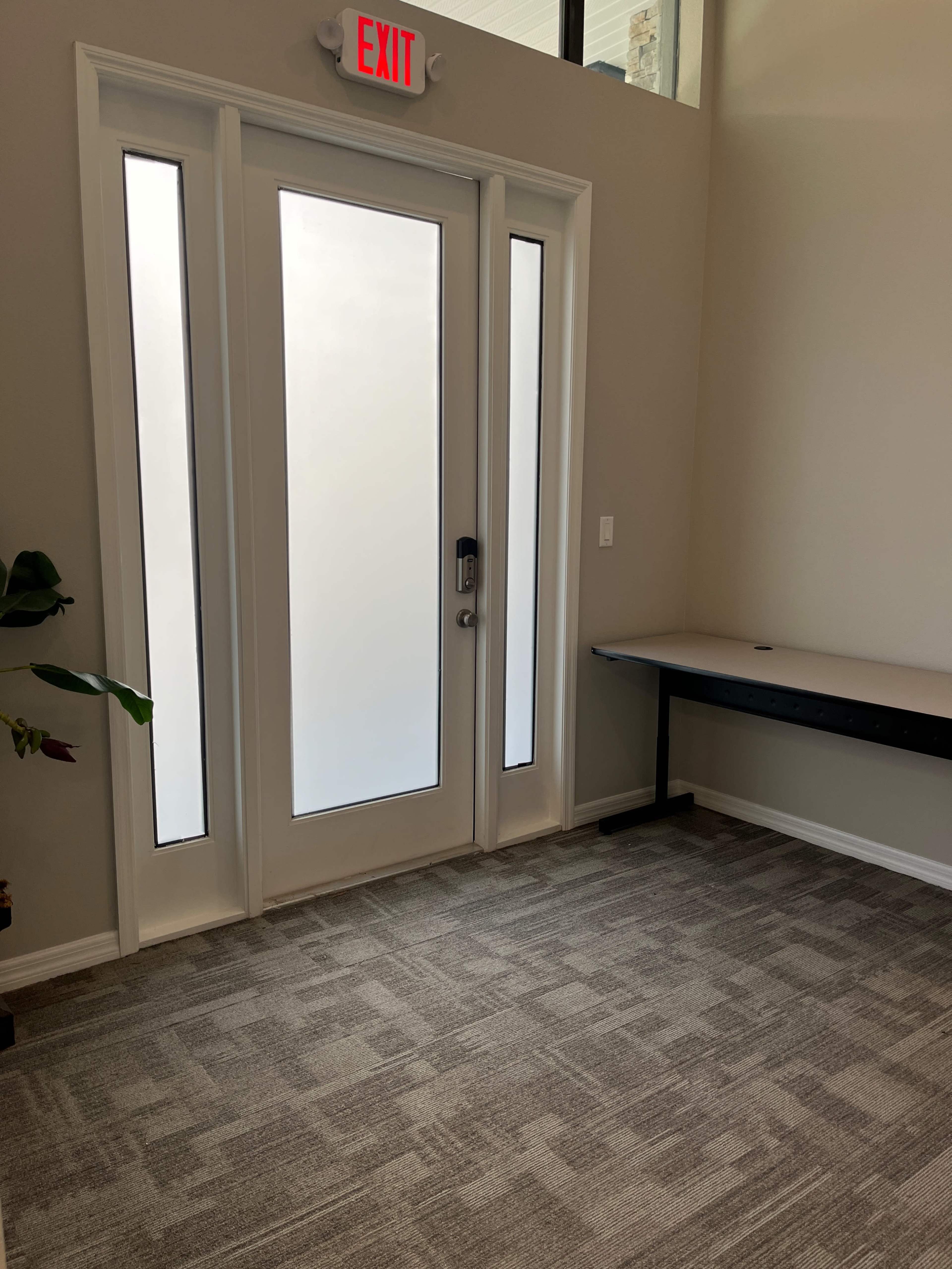 A modern entrance area with a glass door and a small table against the wall.