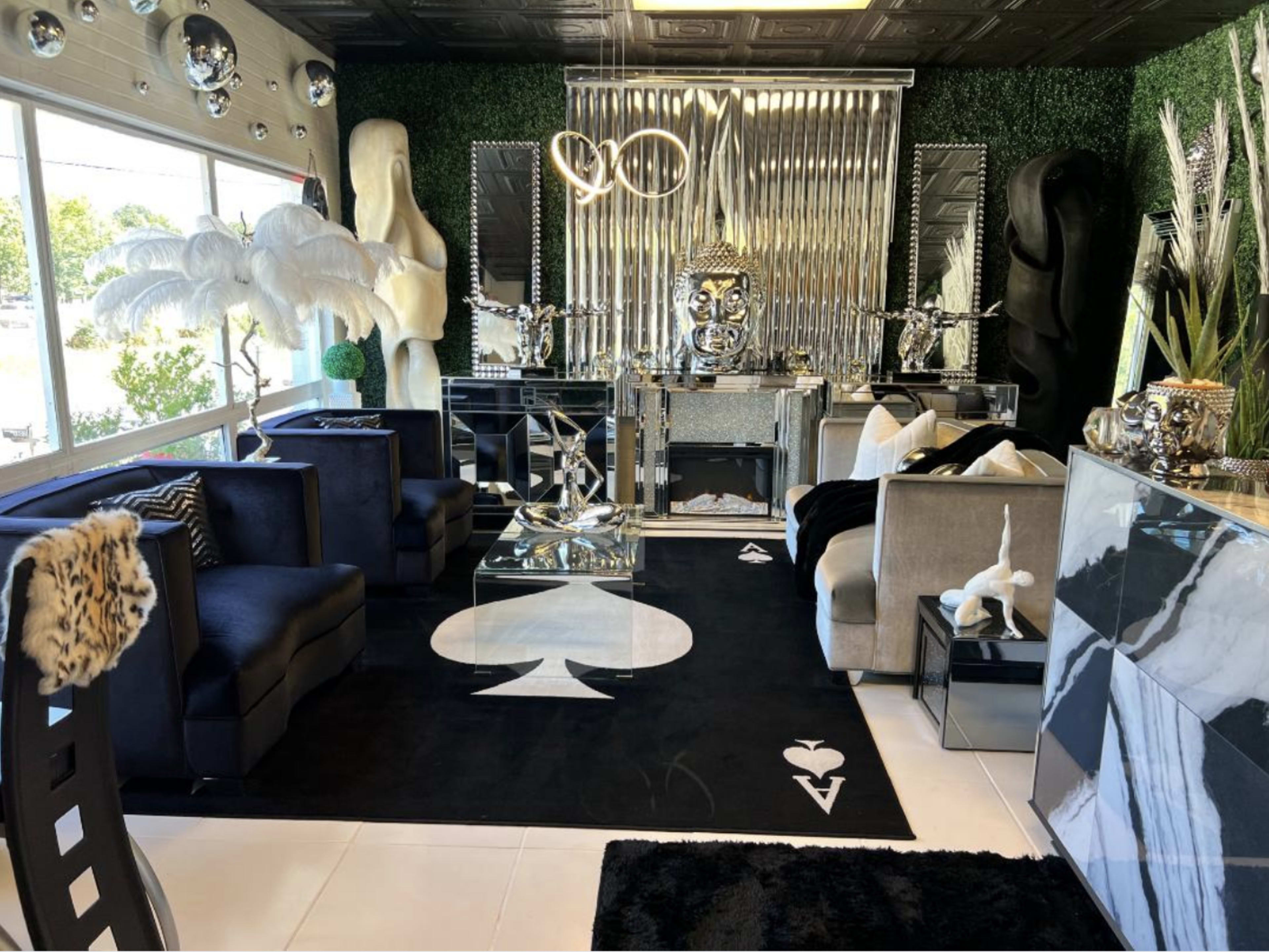 A stylish interior lounge with modern furniture, a black and white color scheme, and decorative accents including plants and sculptures.