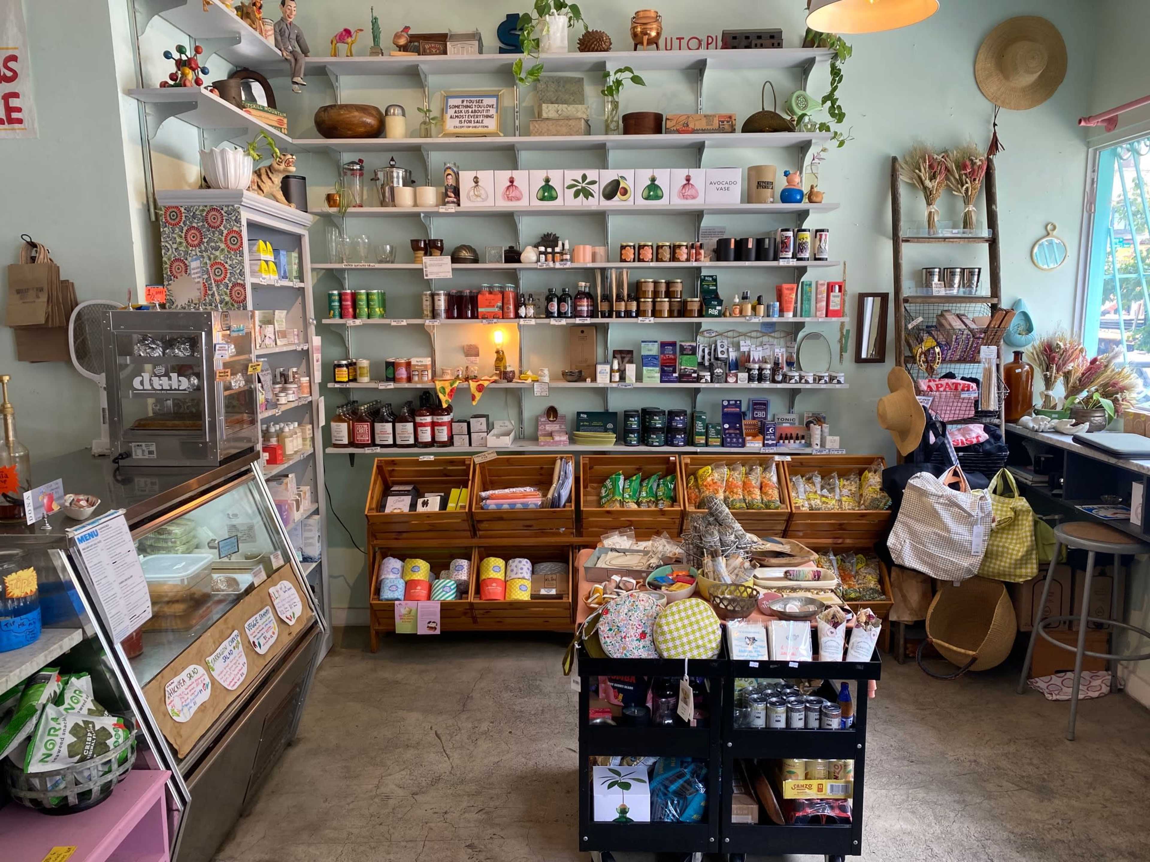 A cozy shop interior with shelves filled with various products, including jars, bottles, and packaged goods, alongside display cases of ice cream and snacks.