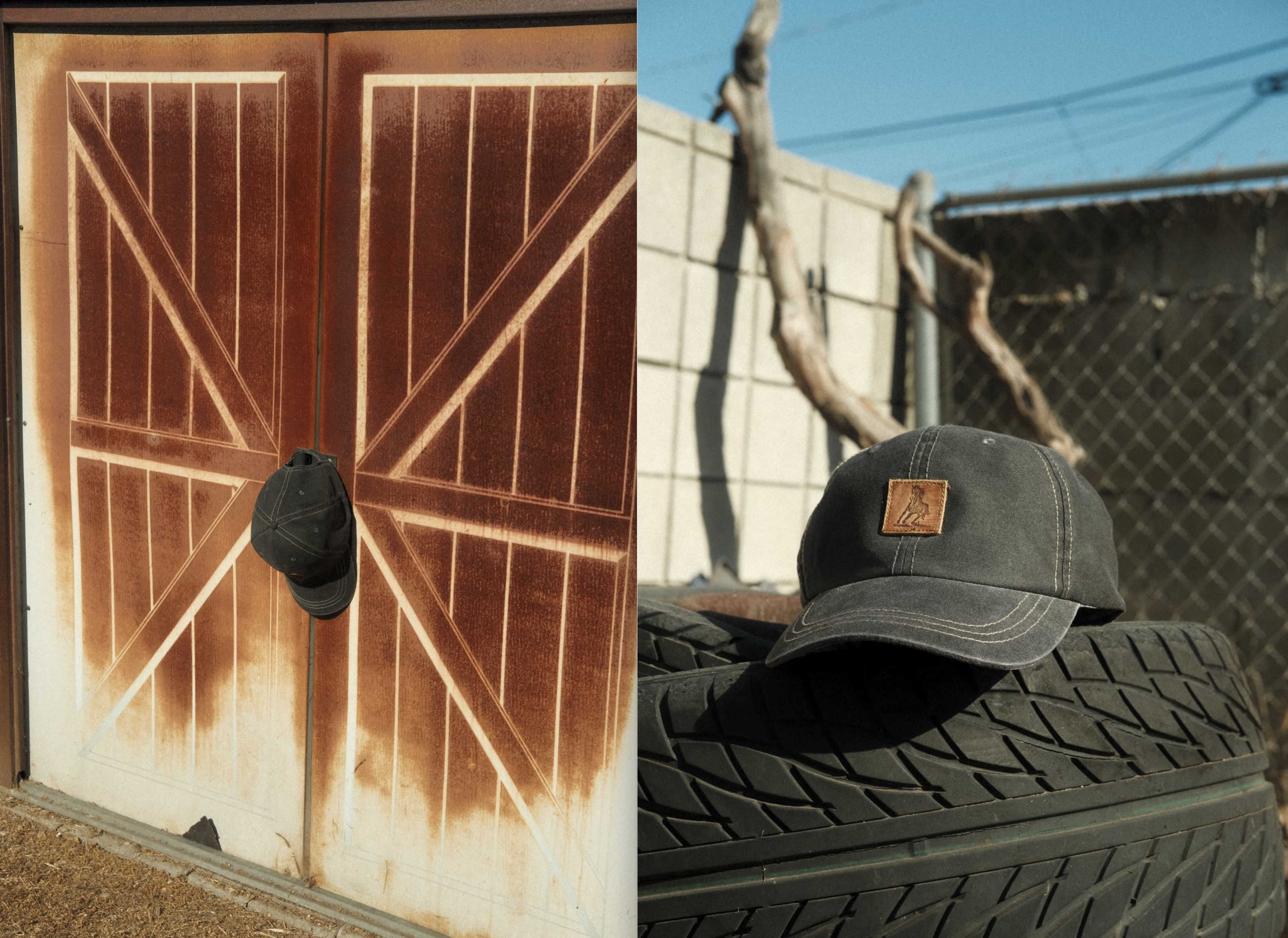 A worn baseball cap hangs on a rusted barn door beside a stacked tire.
