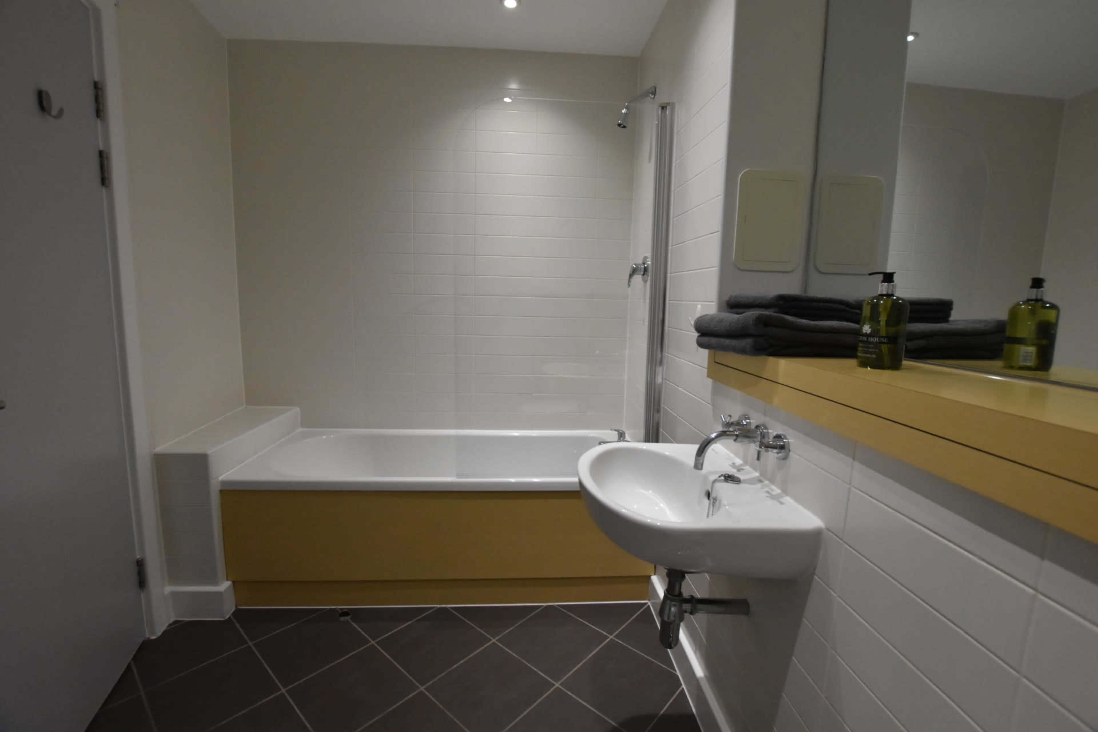 A bathroom equipped with a bathtub, a shower, a sink, and neatly arranged towels on a countertop.
