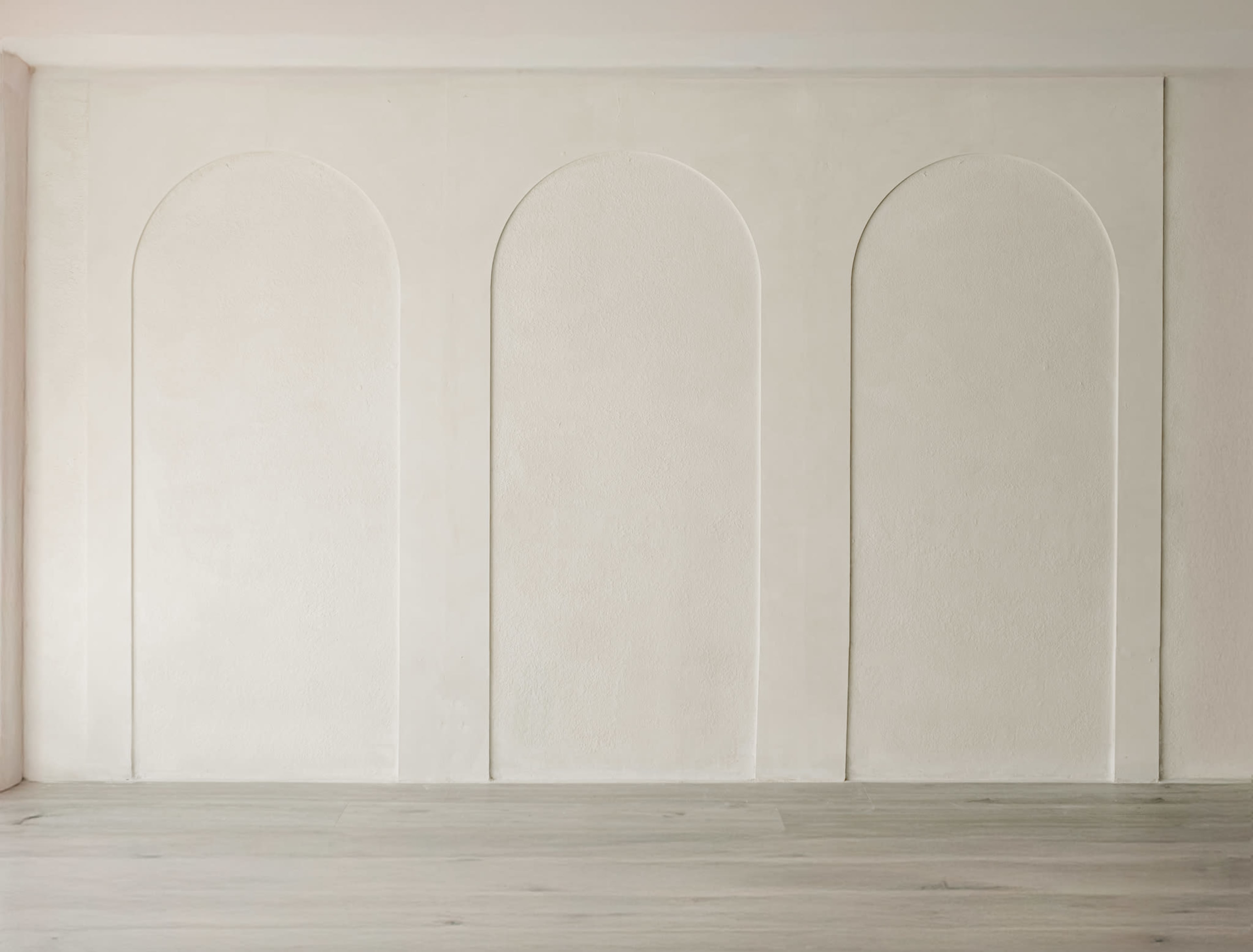 The image features a plain white wall with three arched recesses evenly spaced in a row.