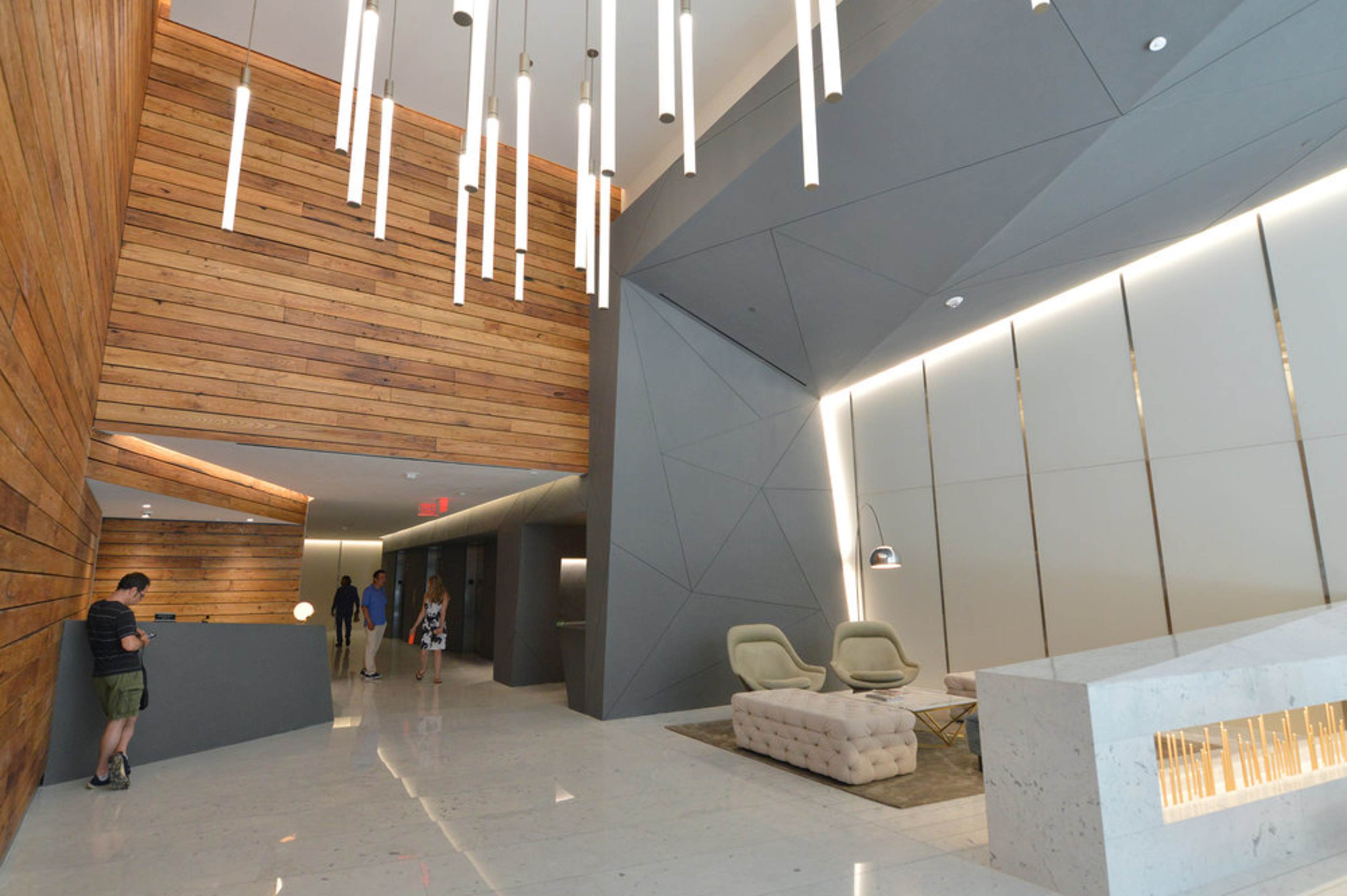 A modern lobby with wood paneling, geometric wall designs, and contemporary seating.