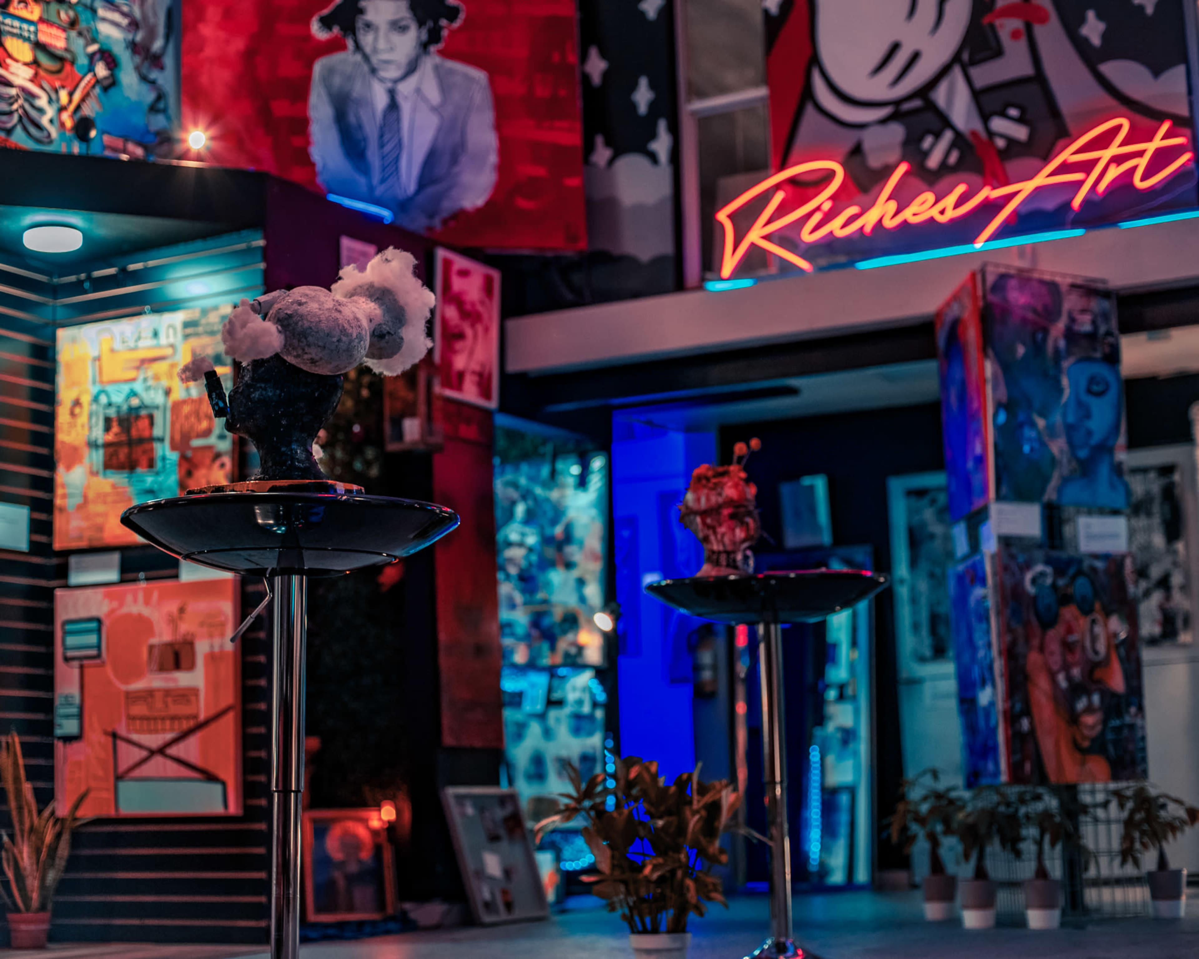 The scene features a vibrant art gallery with neon signage and a display of artwork, including a decorative piece on a black pedestal in the foreground.