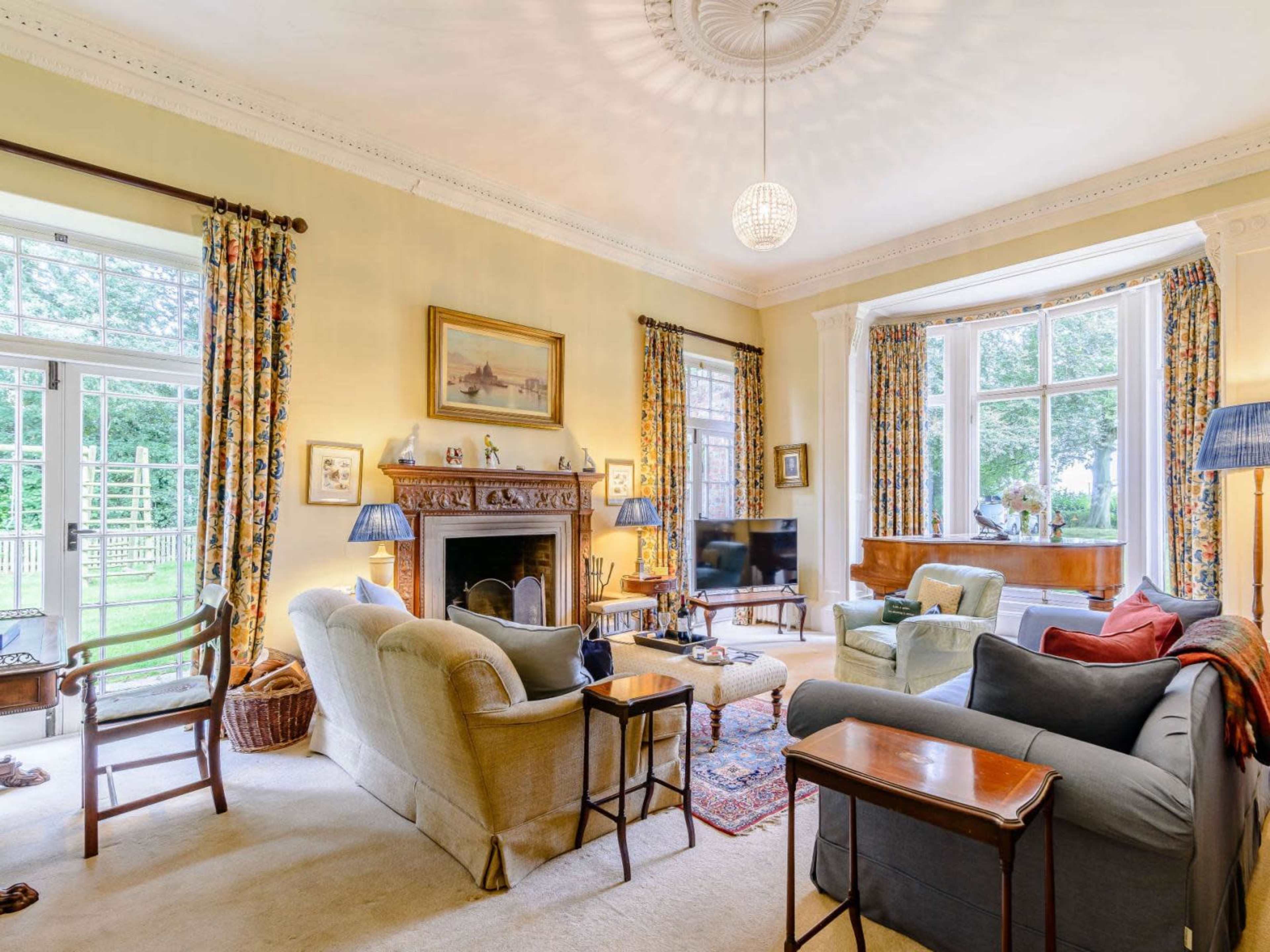 A spacious living room with large windows, a fireplace, and comfortable seating arranged around a coffee table.